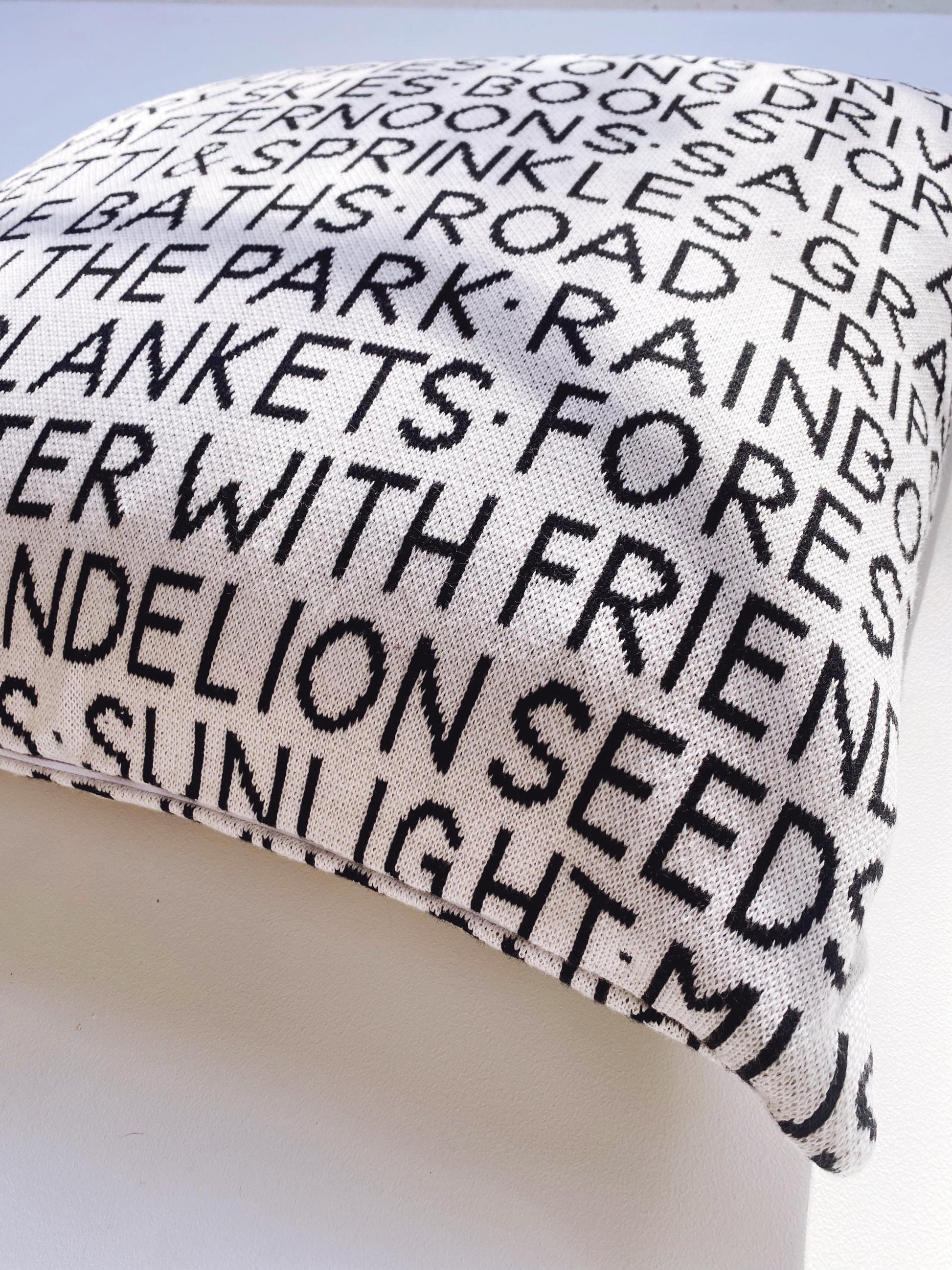Knitted wordy pillow with black text on a white background