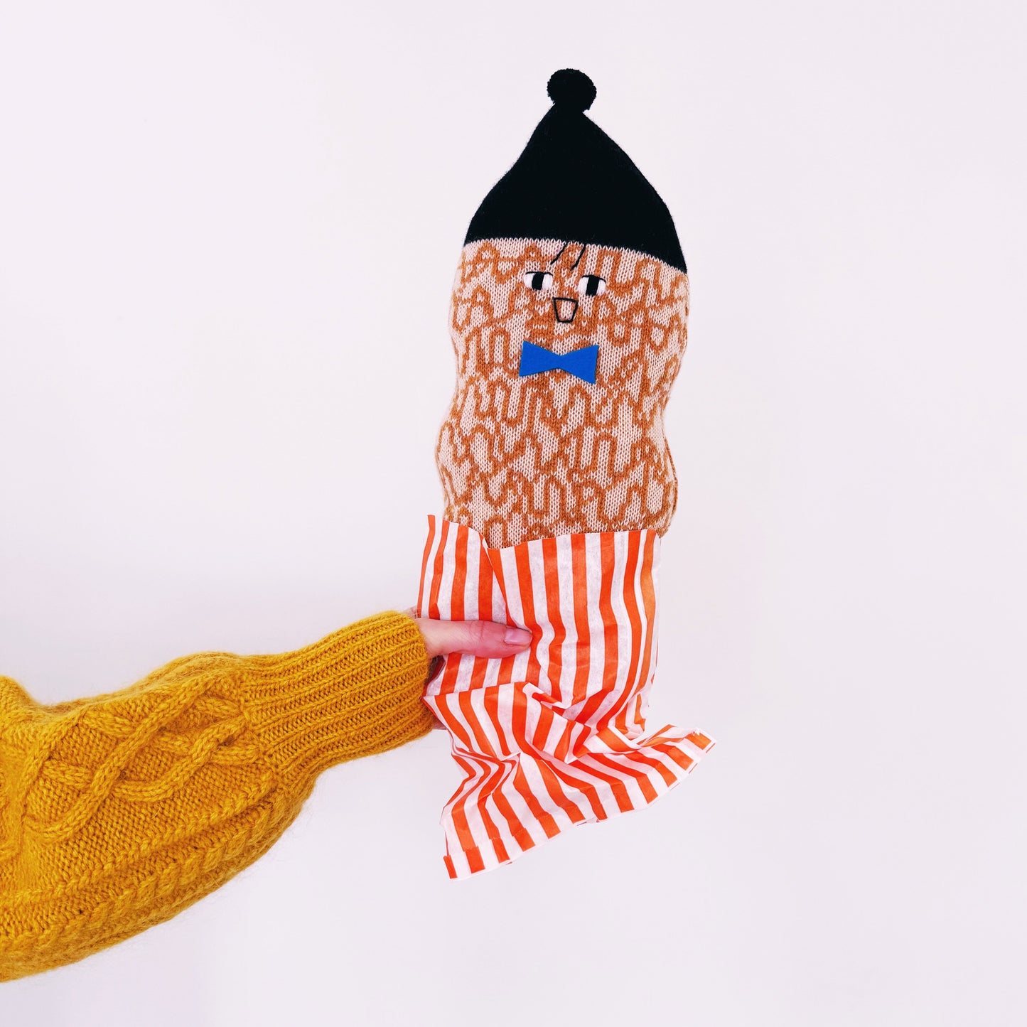Soft knitted lambswool peanut plush toy with a cartoon character design on a white background