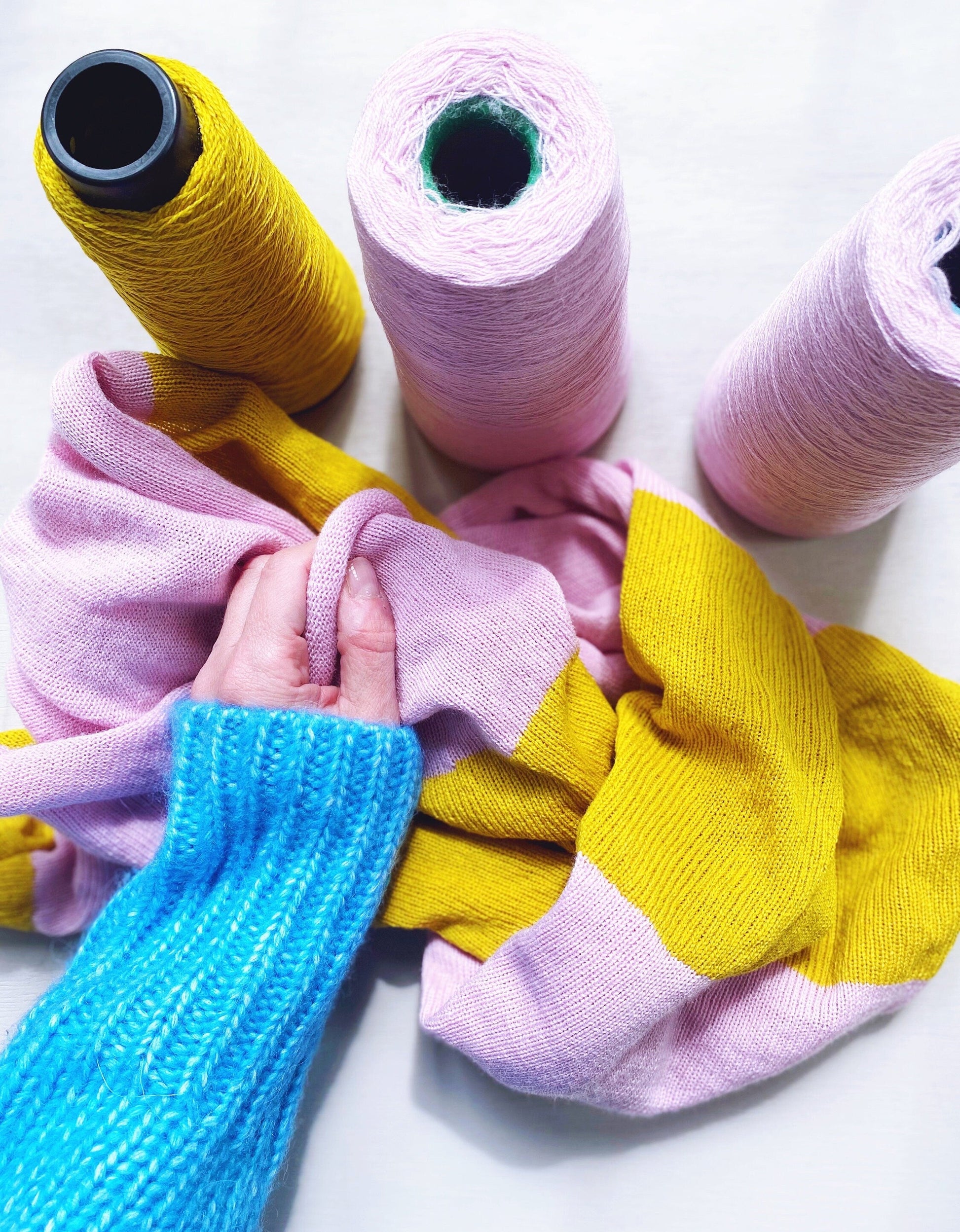Colorful yarn spools and knitted items on a white background