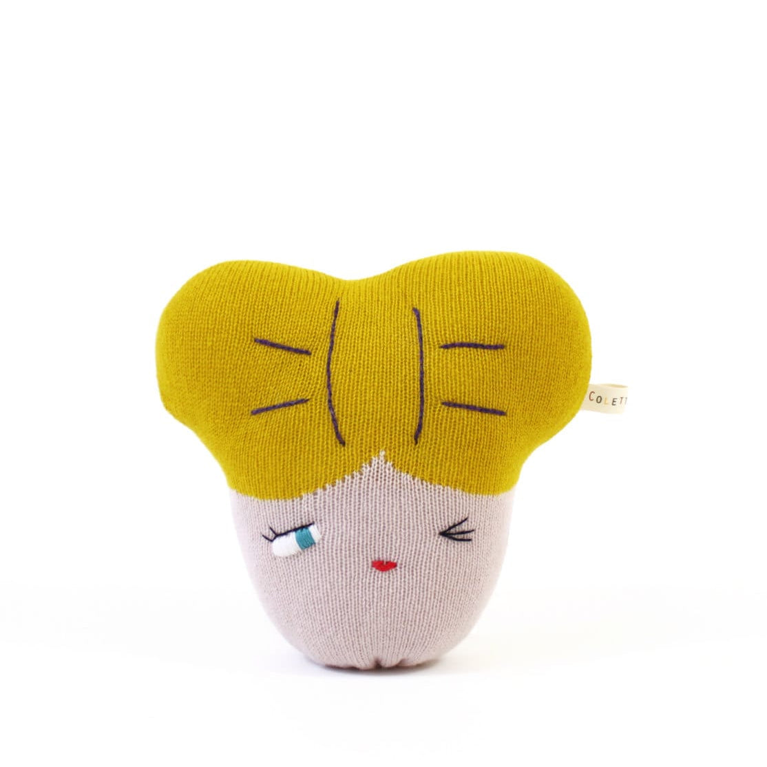 Small knitted plush toy with a yellow bow and pink face on a white background