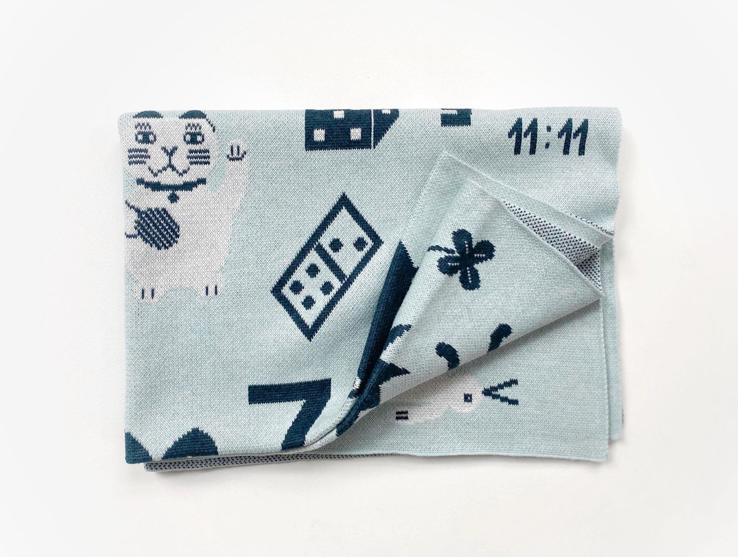 Folded knit baby blanket with blue and white geometric pattern on a white background