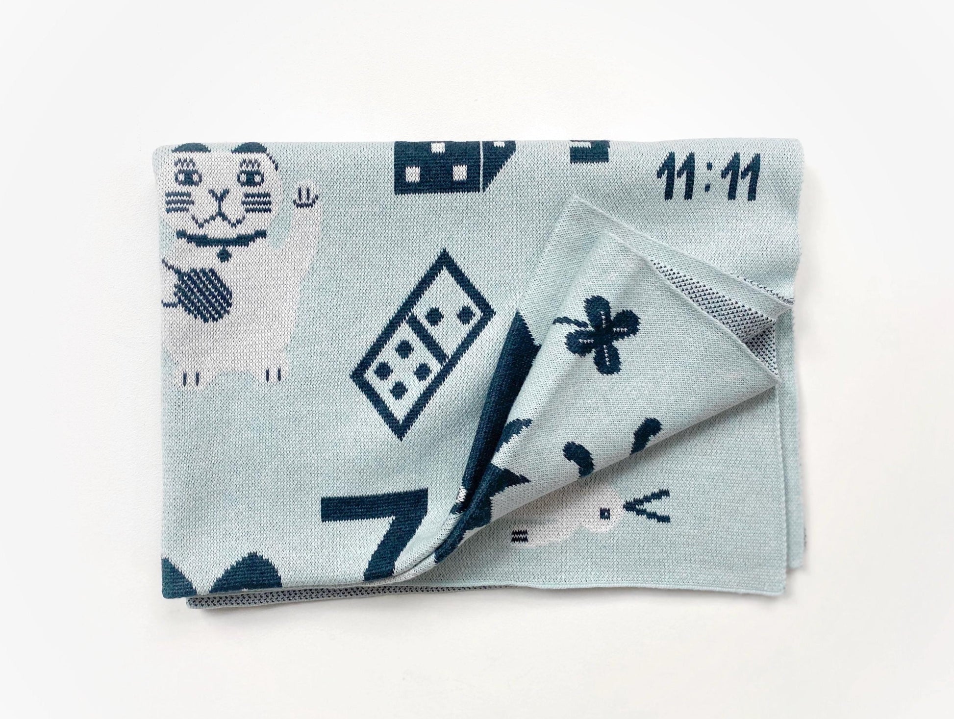 Folded knit baby blanket with blue and white geometric pattern on a white background