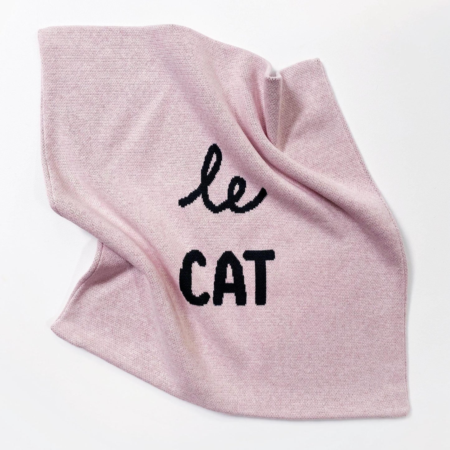 Pink knitted cushion with 'le cat' text on a white background