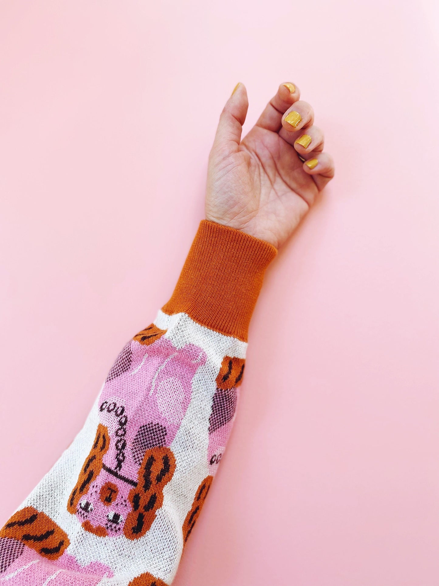 Hand wearing a colorful sleeve with a pink background