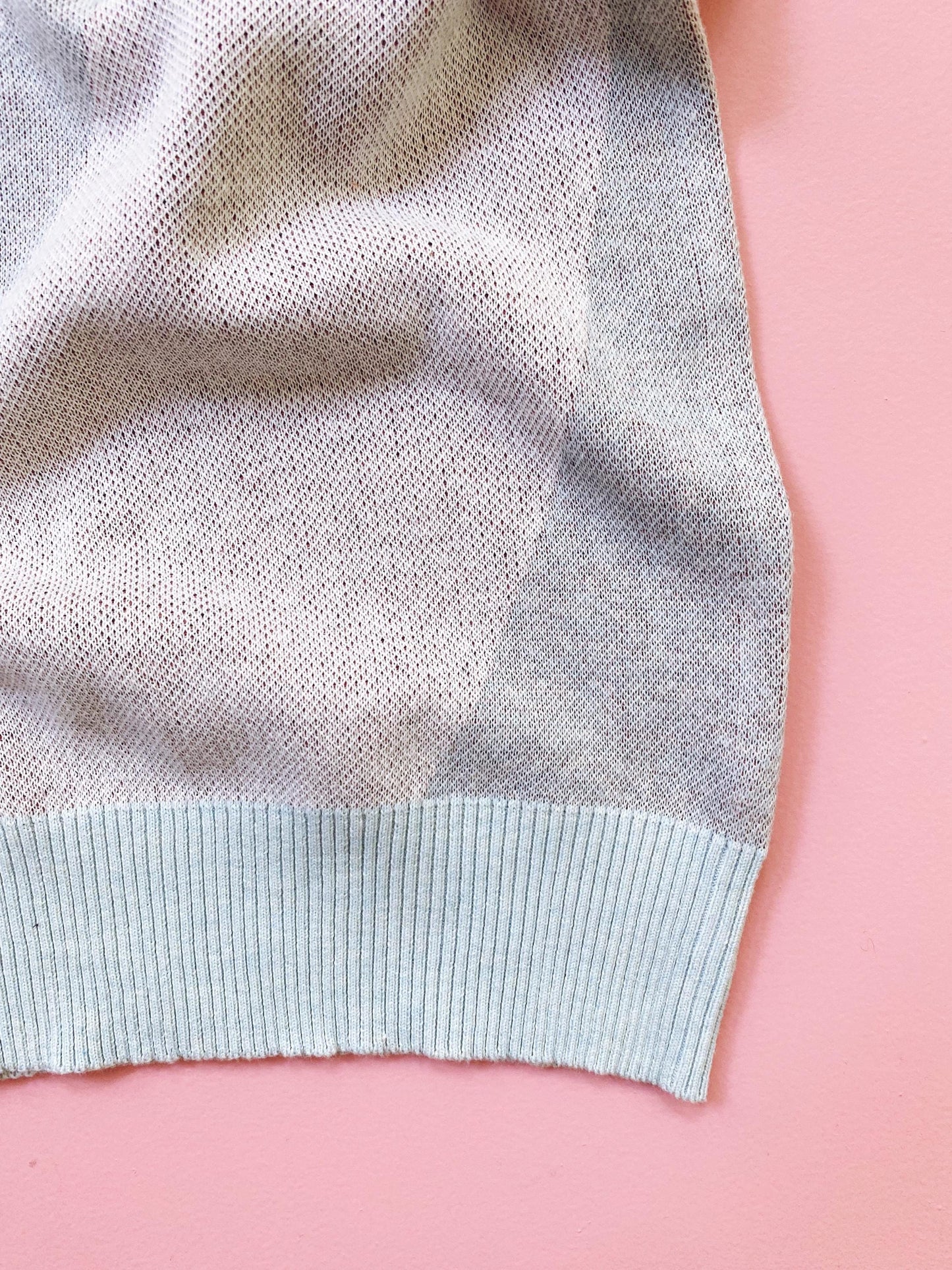 Close-up of a light blue and white knitted textured fabric edge on a pink background