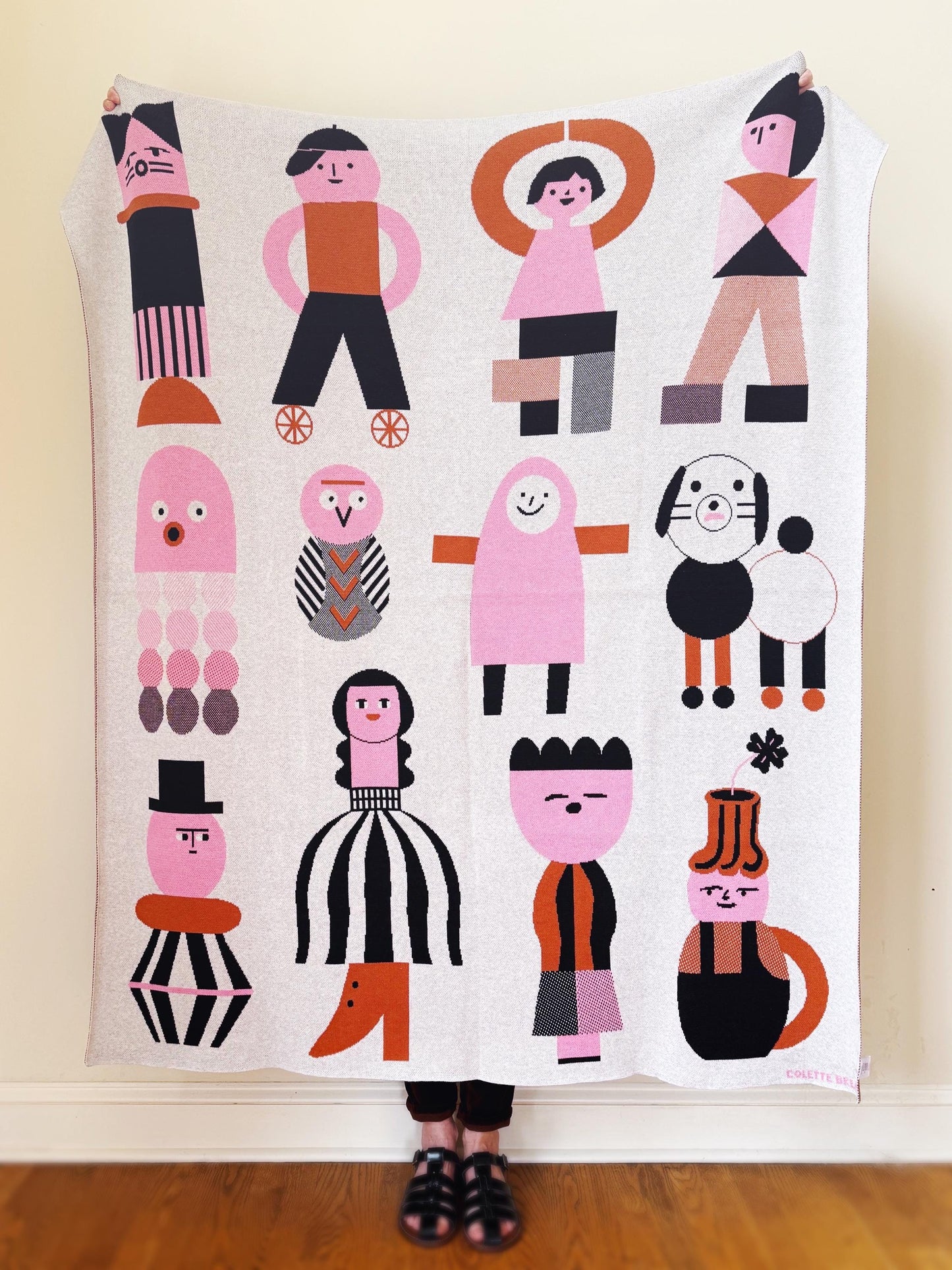 Knitted lanket with colorful abstract design on a wooden floor.