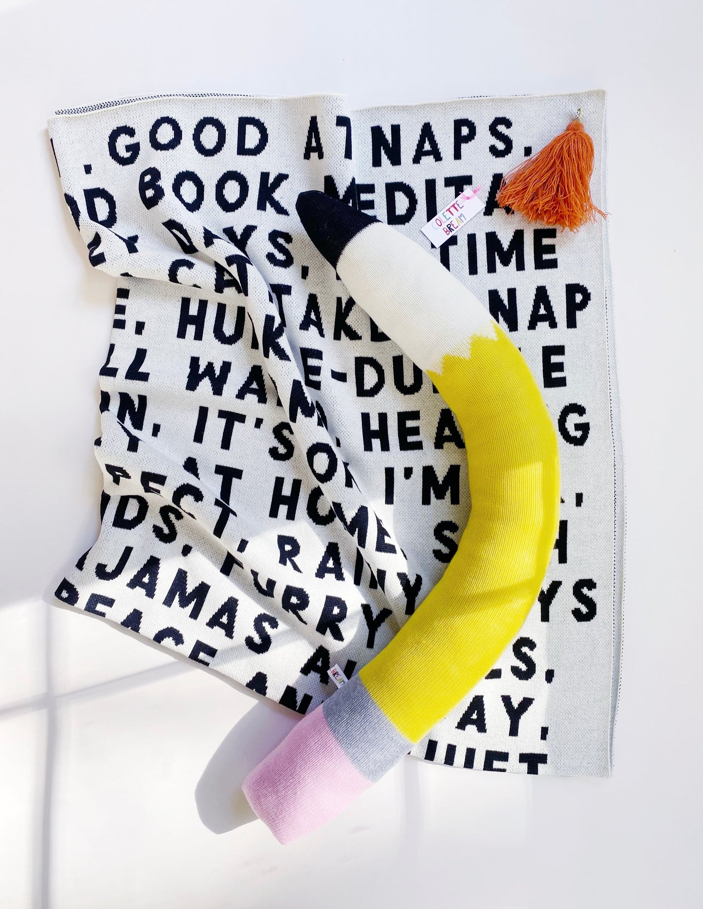 Large knitted lambswool pencil-shaped pillow on a blanket with text