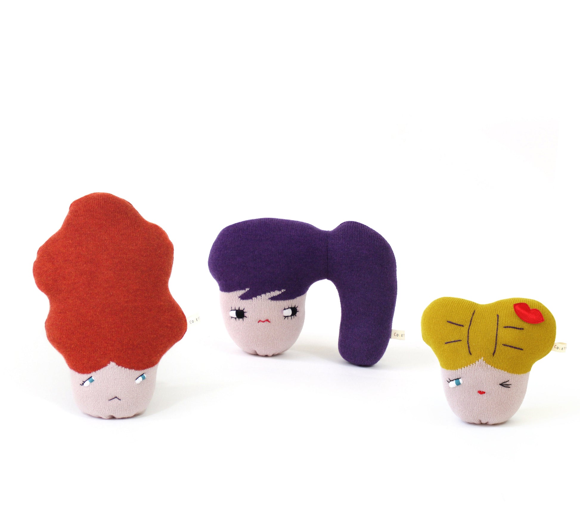 Three knitted lambswool plush toys with different faces and hairstyles on a white background