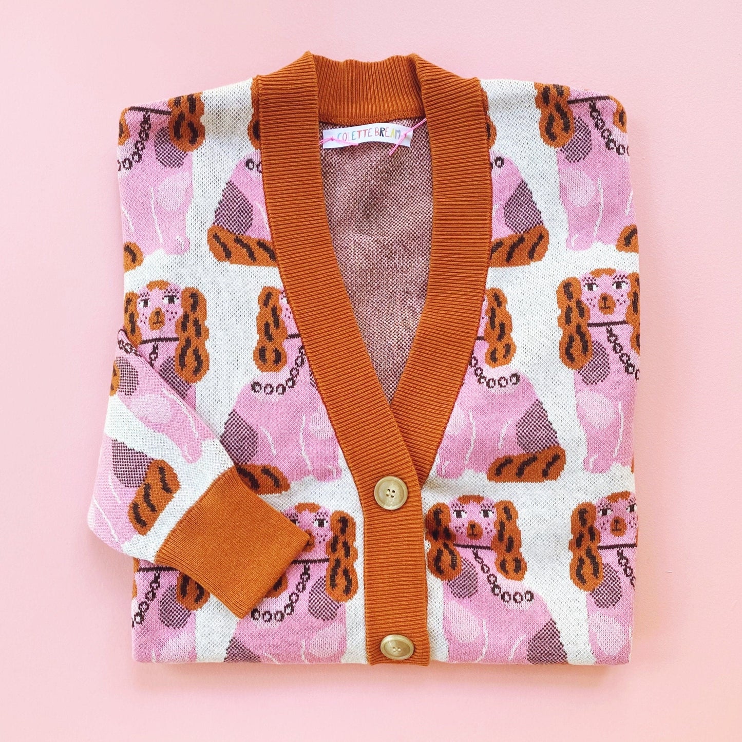 Folded cardigan with pink pattern of Staffordshire dogs on a pink background