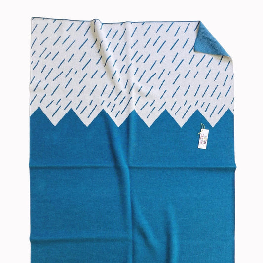 Blue blanket with white patterned border on a white background