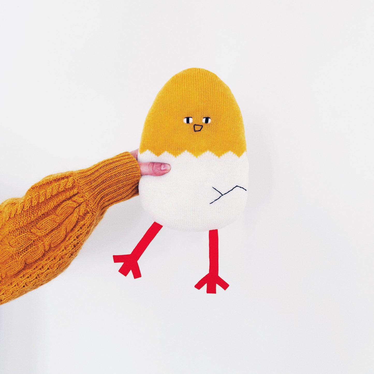 Lambswool Knitted yellow and white chick egg toy with a red mouth on a white background
