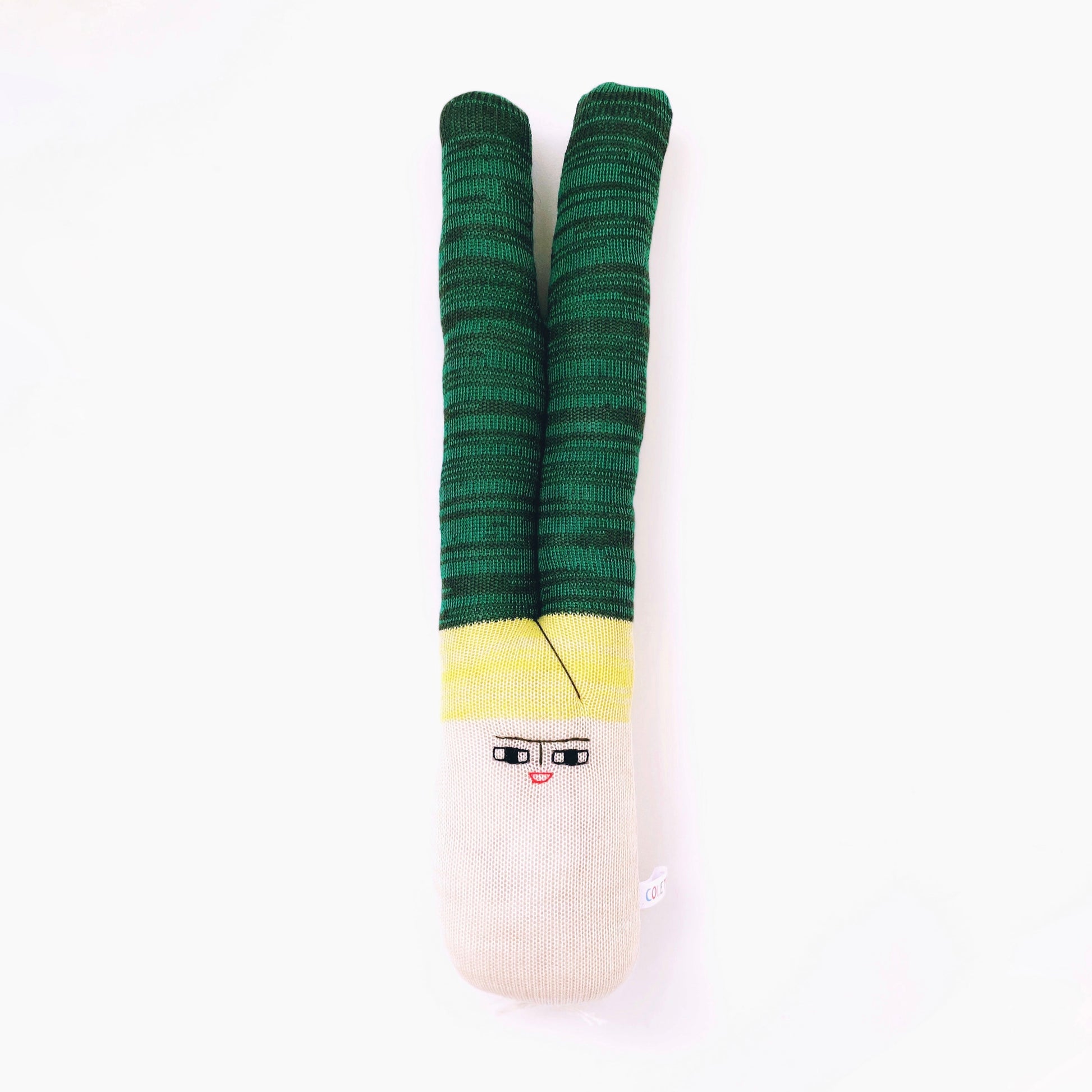 Green and yellow leek toy plush with a face design on a white background
