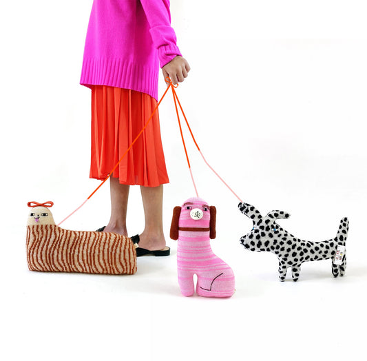 Person holding a leash with three plush dog toys on a white background