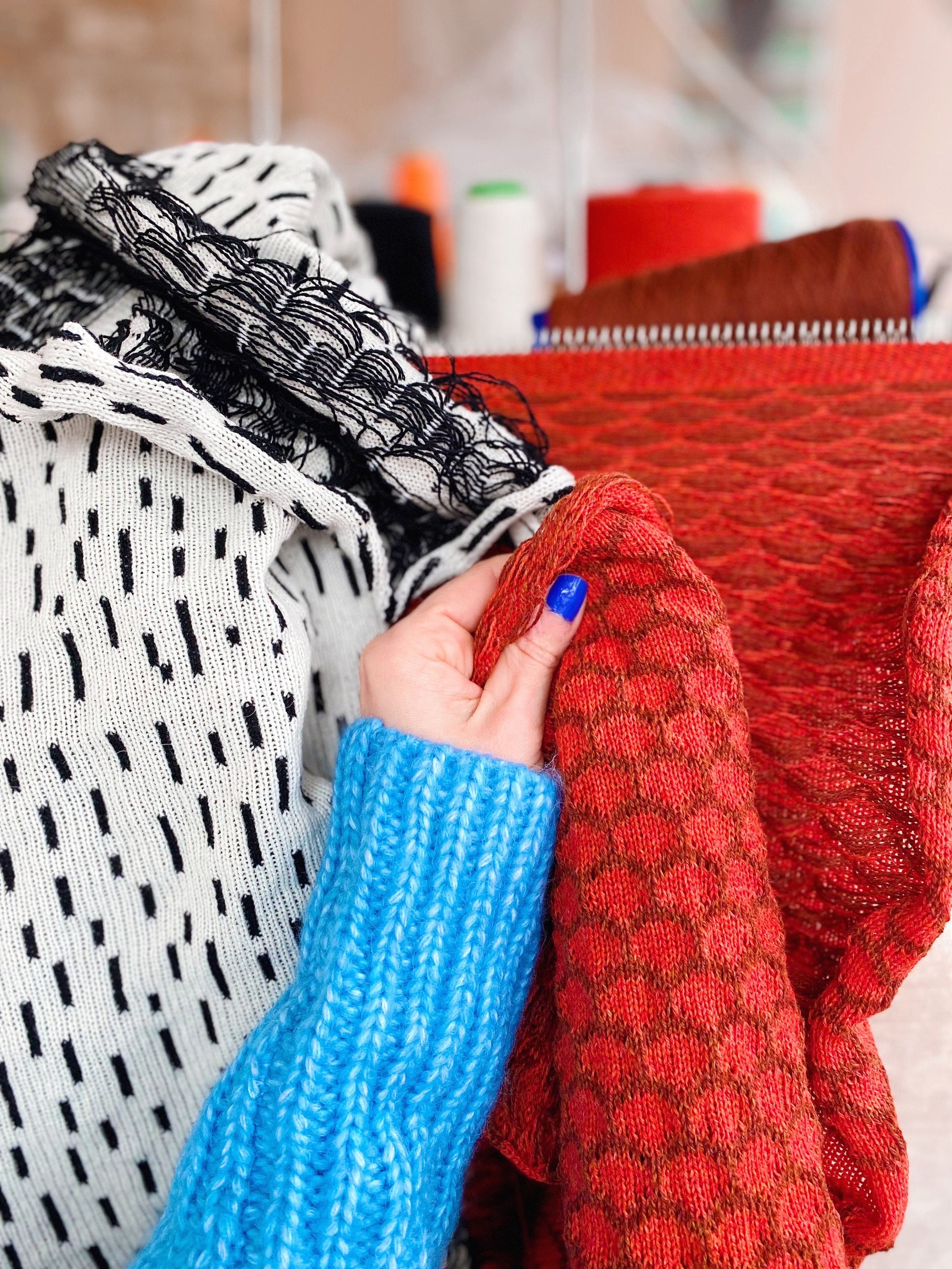 Person holding a knitted fabric with a blurred background of clothes