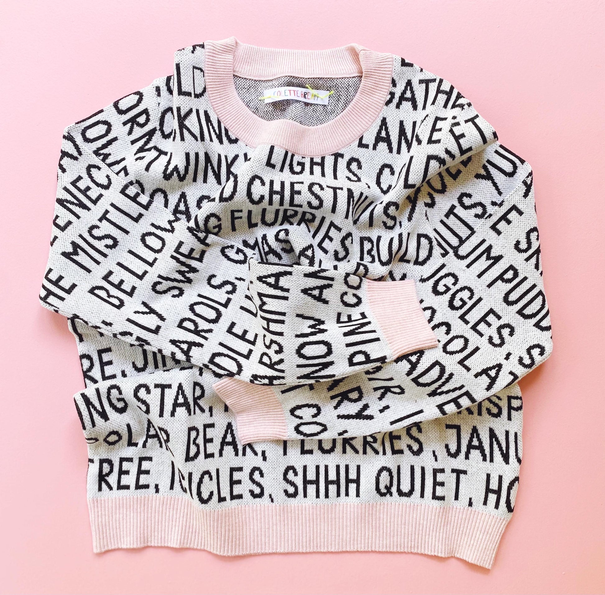 Sweater with christmas text pattern on a pink background