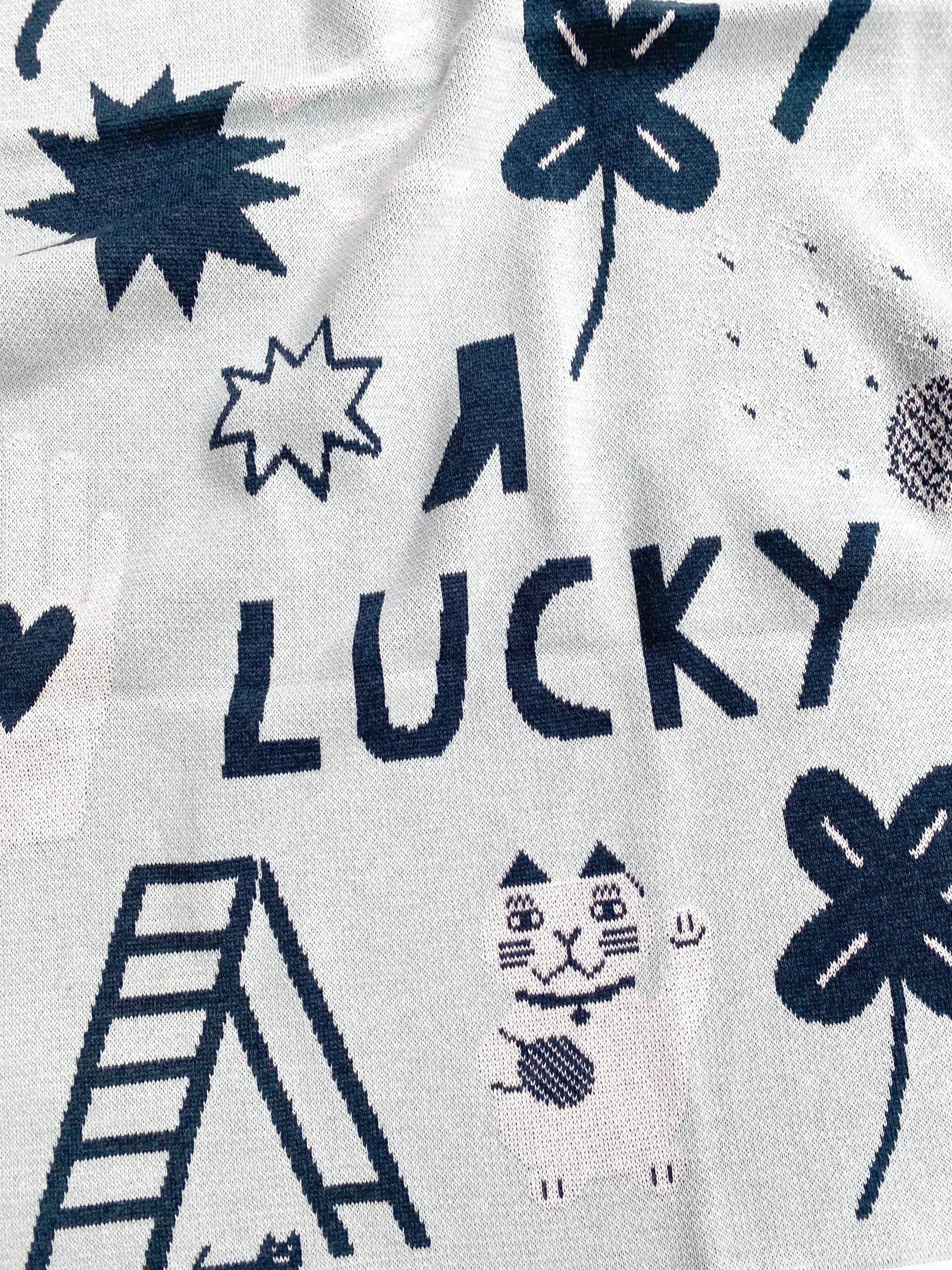 A detail of a knitted fabric with navy blue lucky symbols on a white background