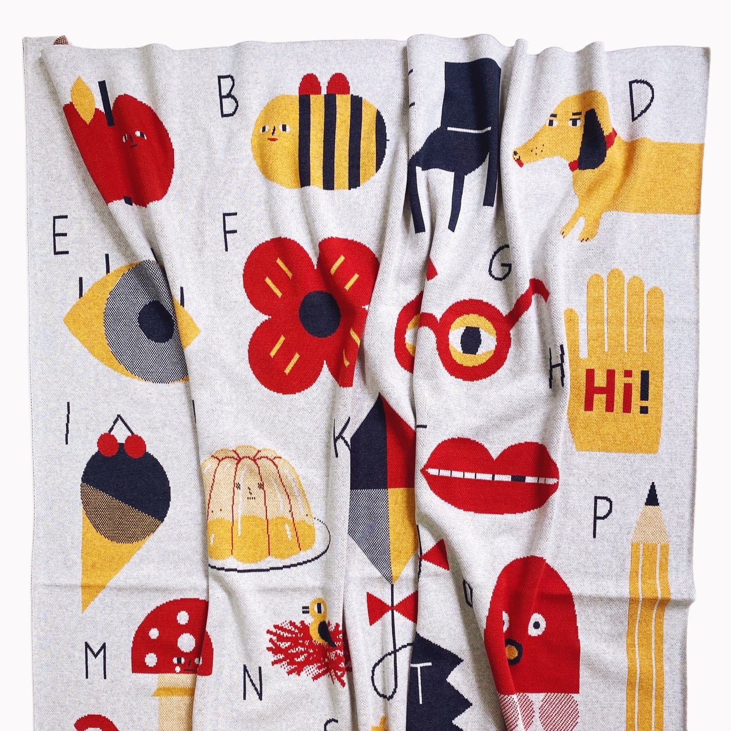 Colorful knit Alphabet blanket throw with various illustrations and letters on a white background