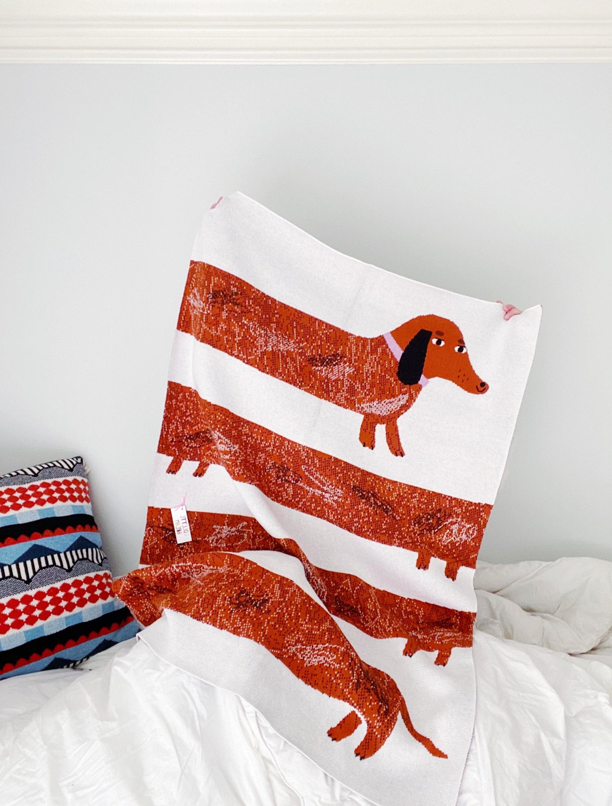 Knit decorative blanket with dachshund design on a bed