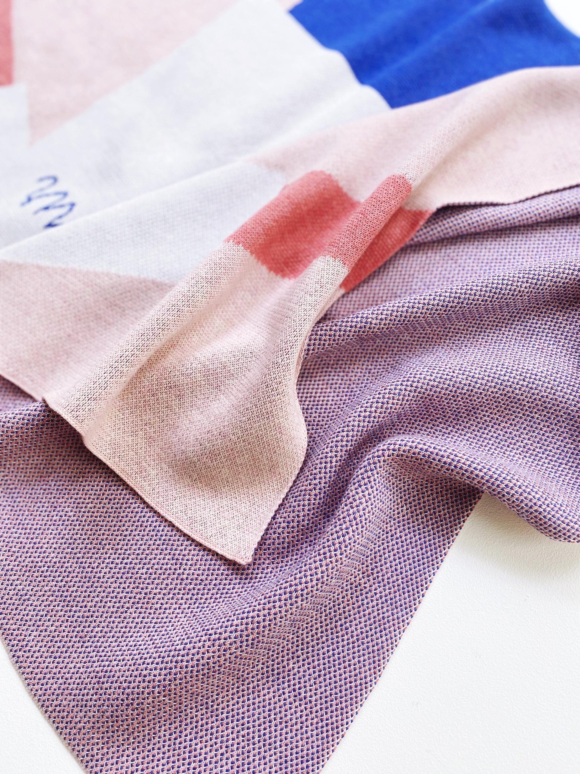 Close-up of knit fabric swatches in pink, blue, and purple on a white background