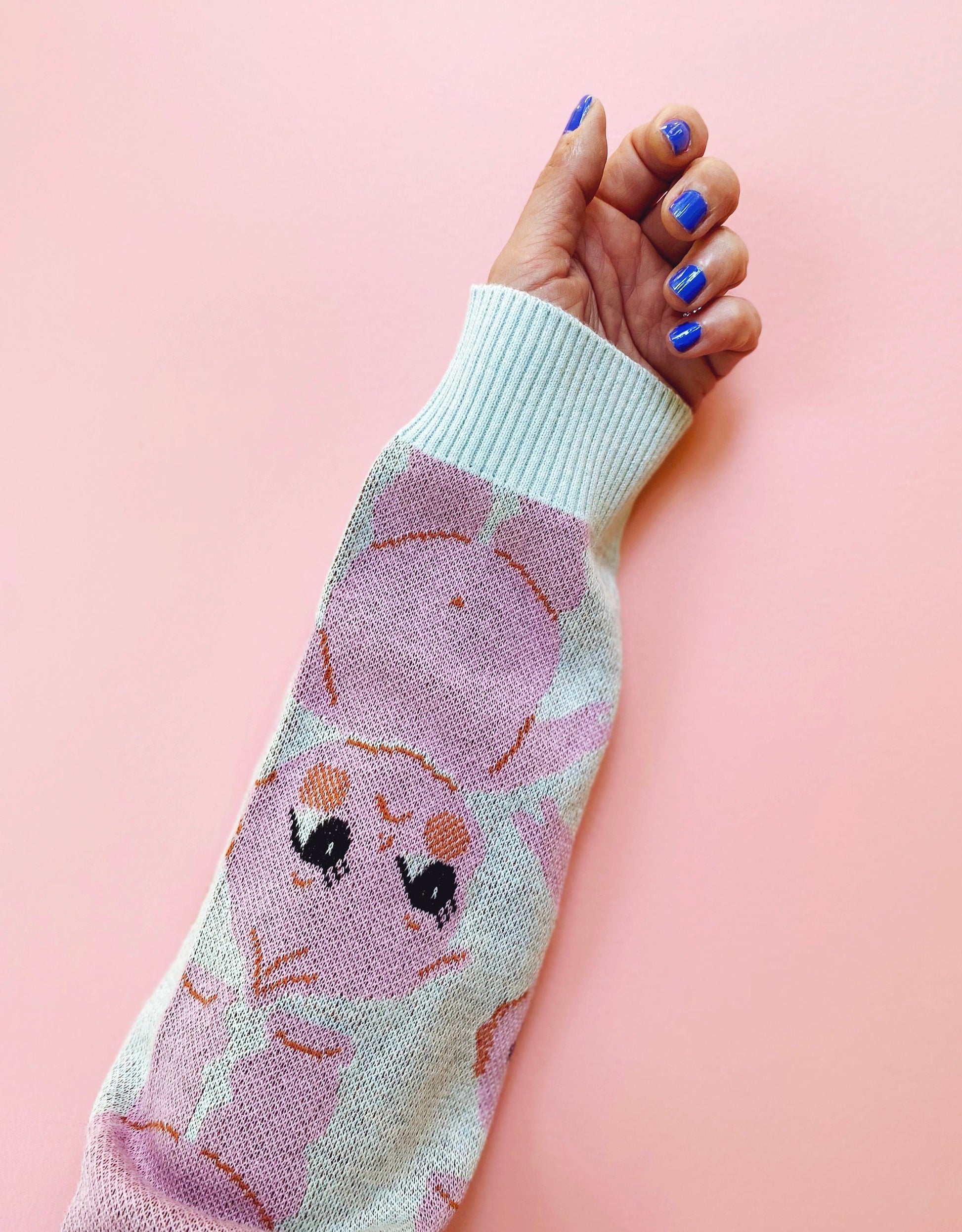 Sweater sleeve with cartoon kewpie character design on a pink background