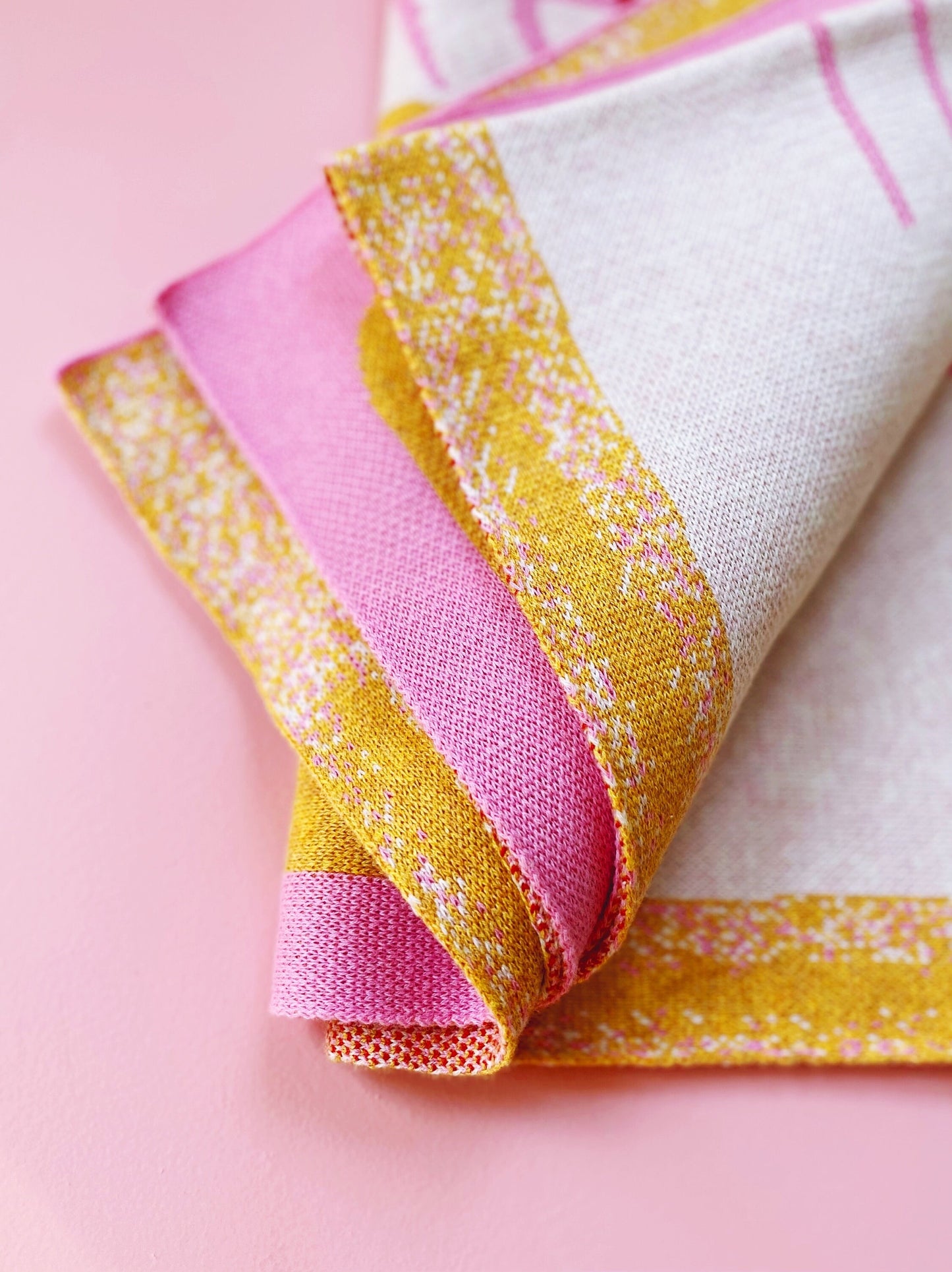 Folded knit fabric with pink and yellow pattern on a pink background