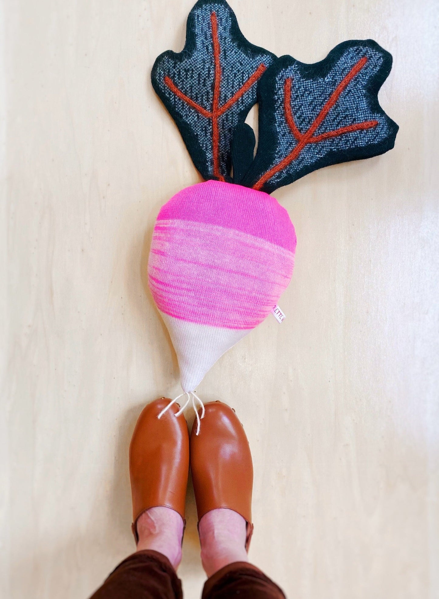 Decorative radish pillow on a light wooden floor