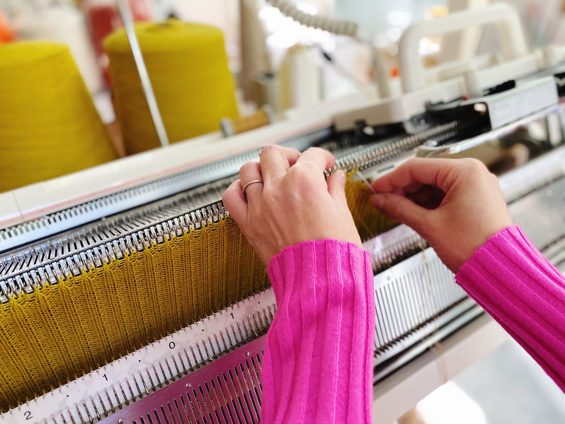 Person working with yarn on a knitting machine in a workshop setting