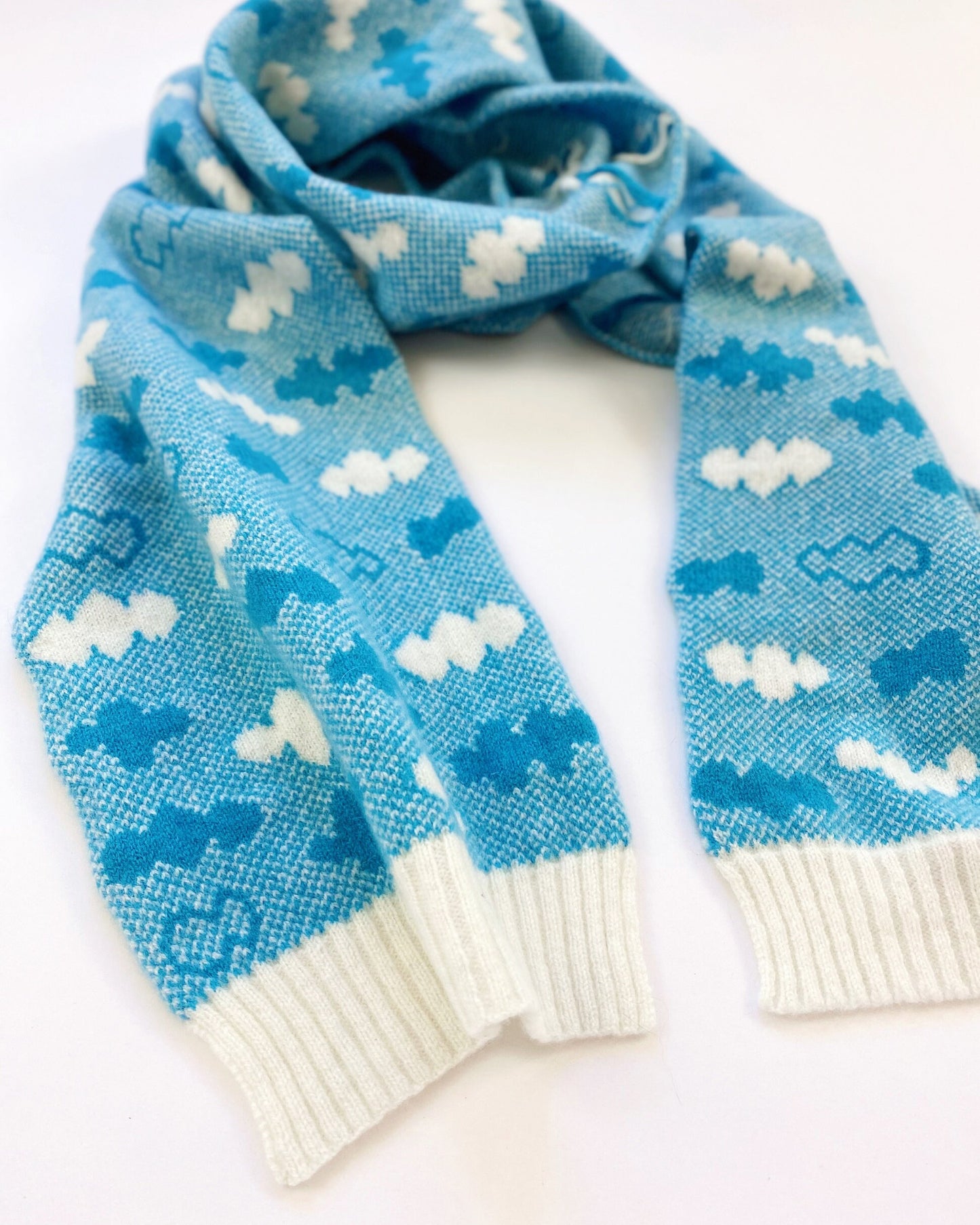 Blue knitted scarf with cloud pattern on a white background