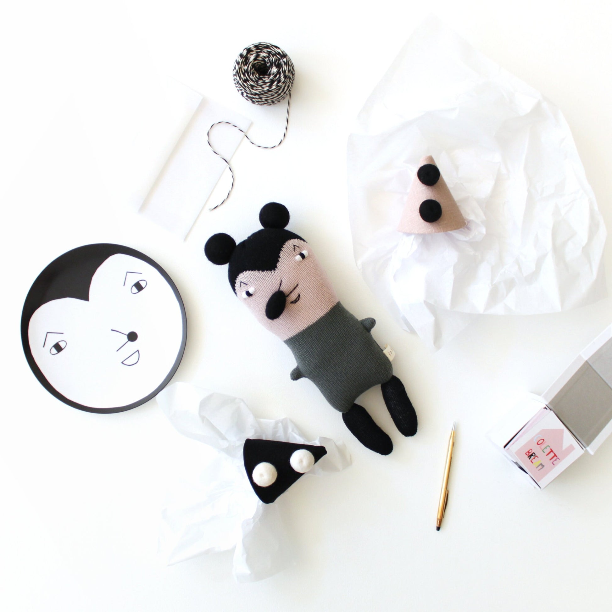 Handmade knitted plush toy mouse with black and white design on a white background