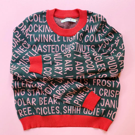 Knitted holiday sweater with festive christmas text pattern on a pink background