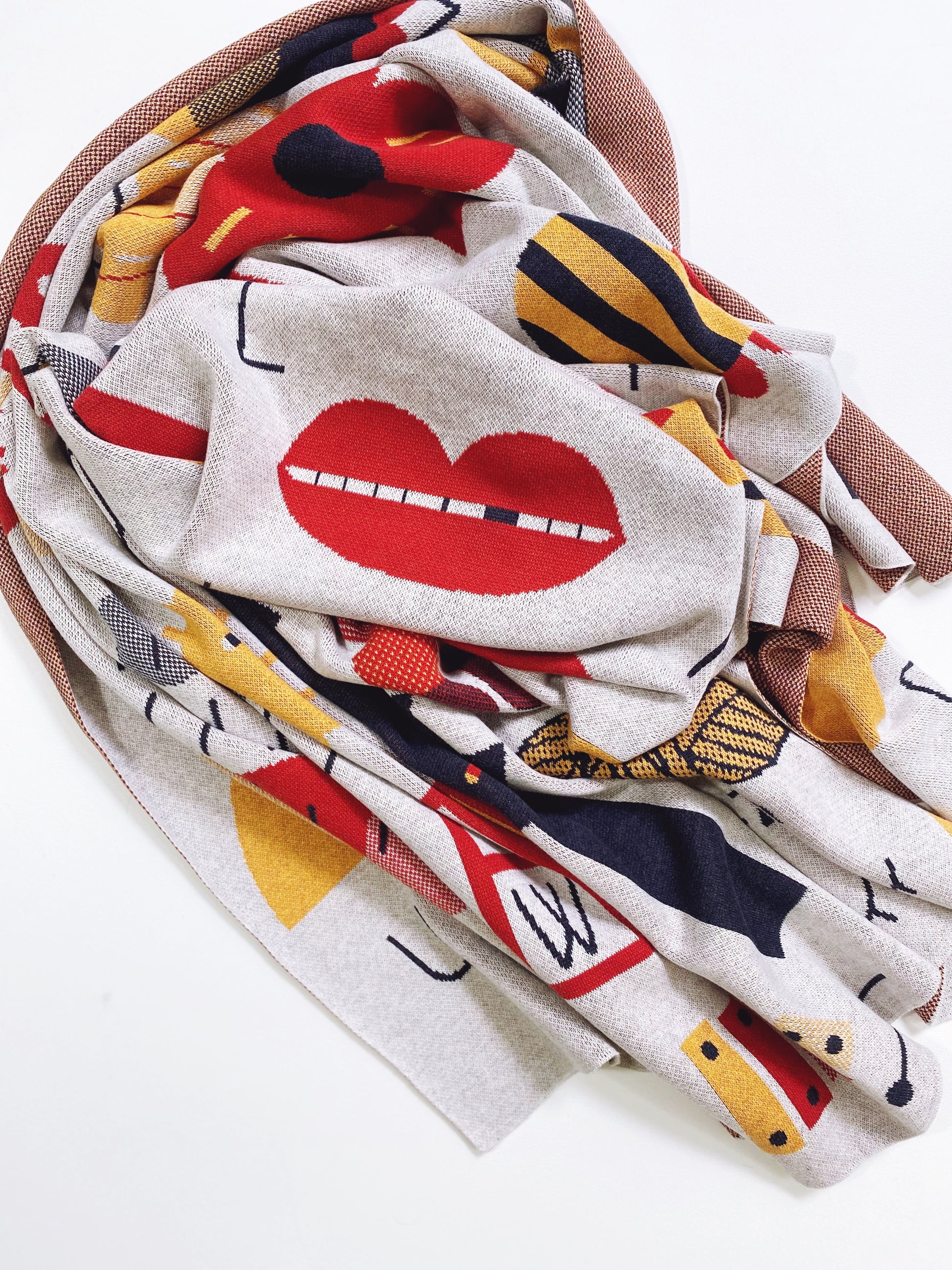 Colorful knit alphabet throw with L for lips and heart designs on a white background
