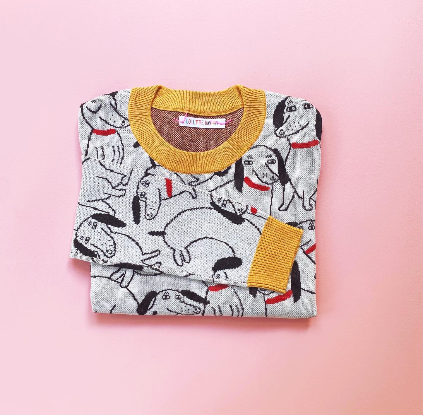 Folded sweater with sausage dog pattern on a pink background