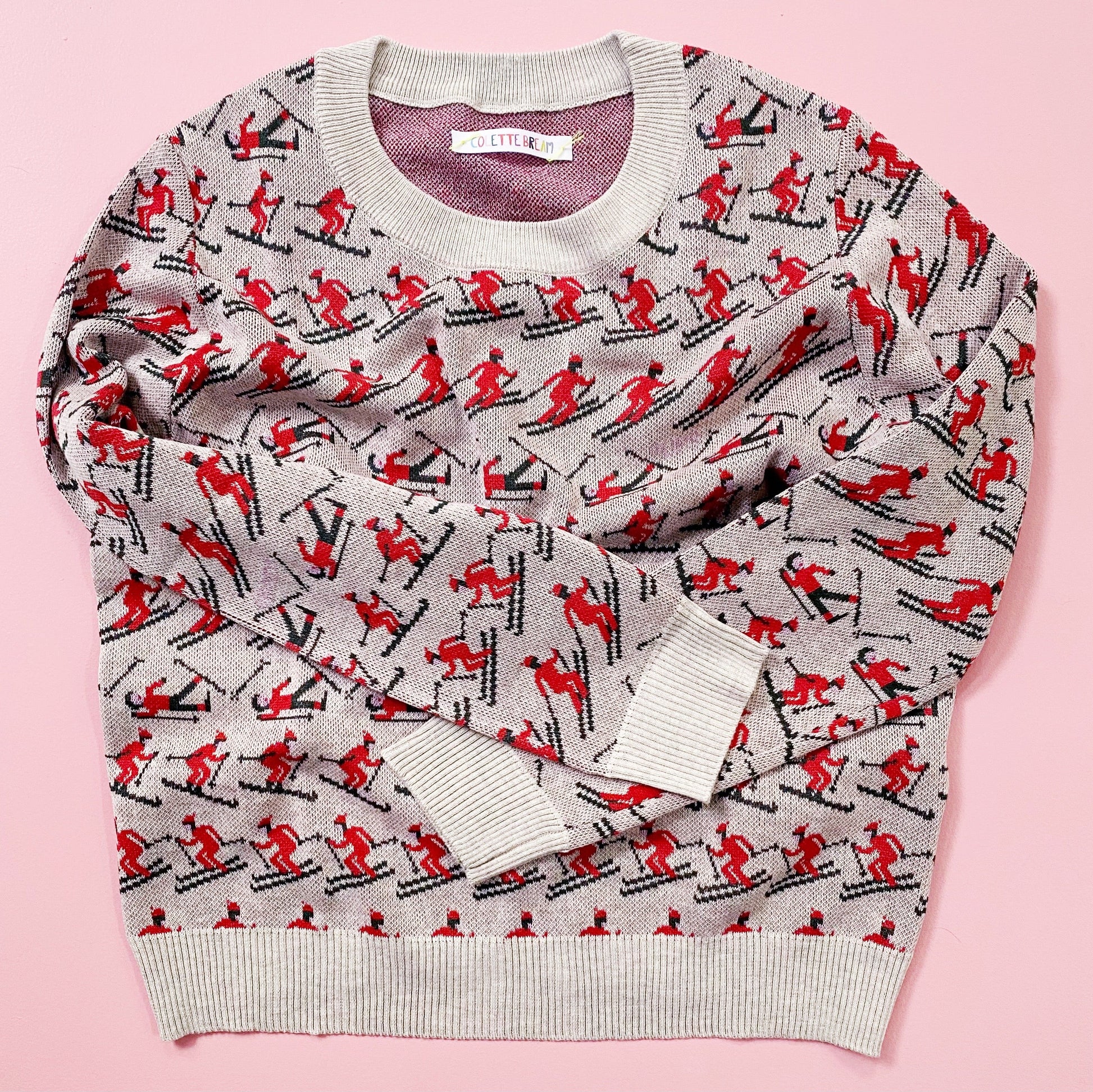 Sweater with red and black pattern of skiers on a pink background