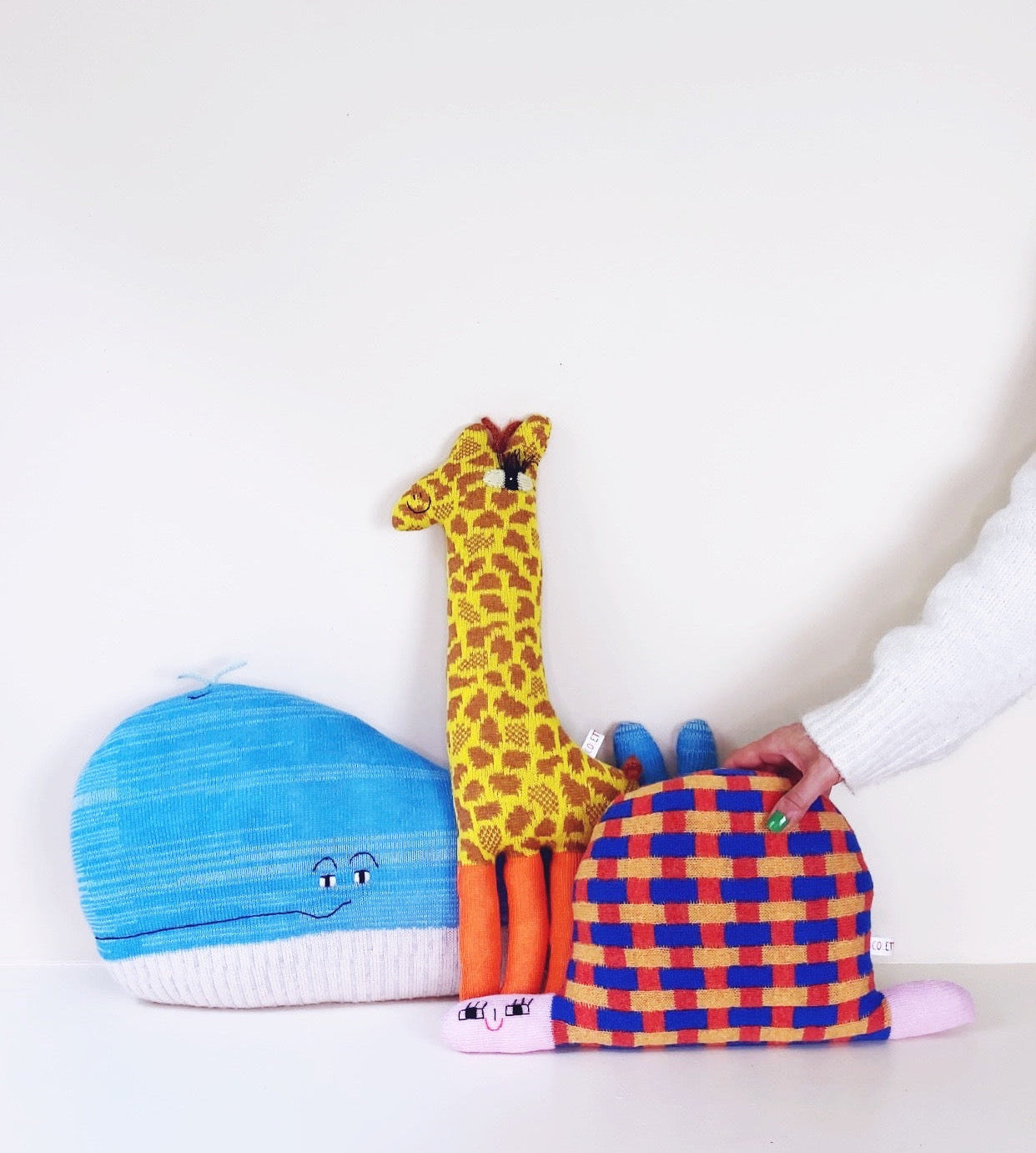 Colorful soft knitted plush toys including a giraffe, whale, and tur on a white backgroundle