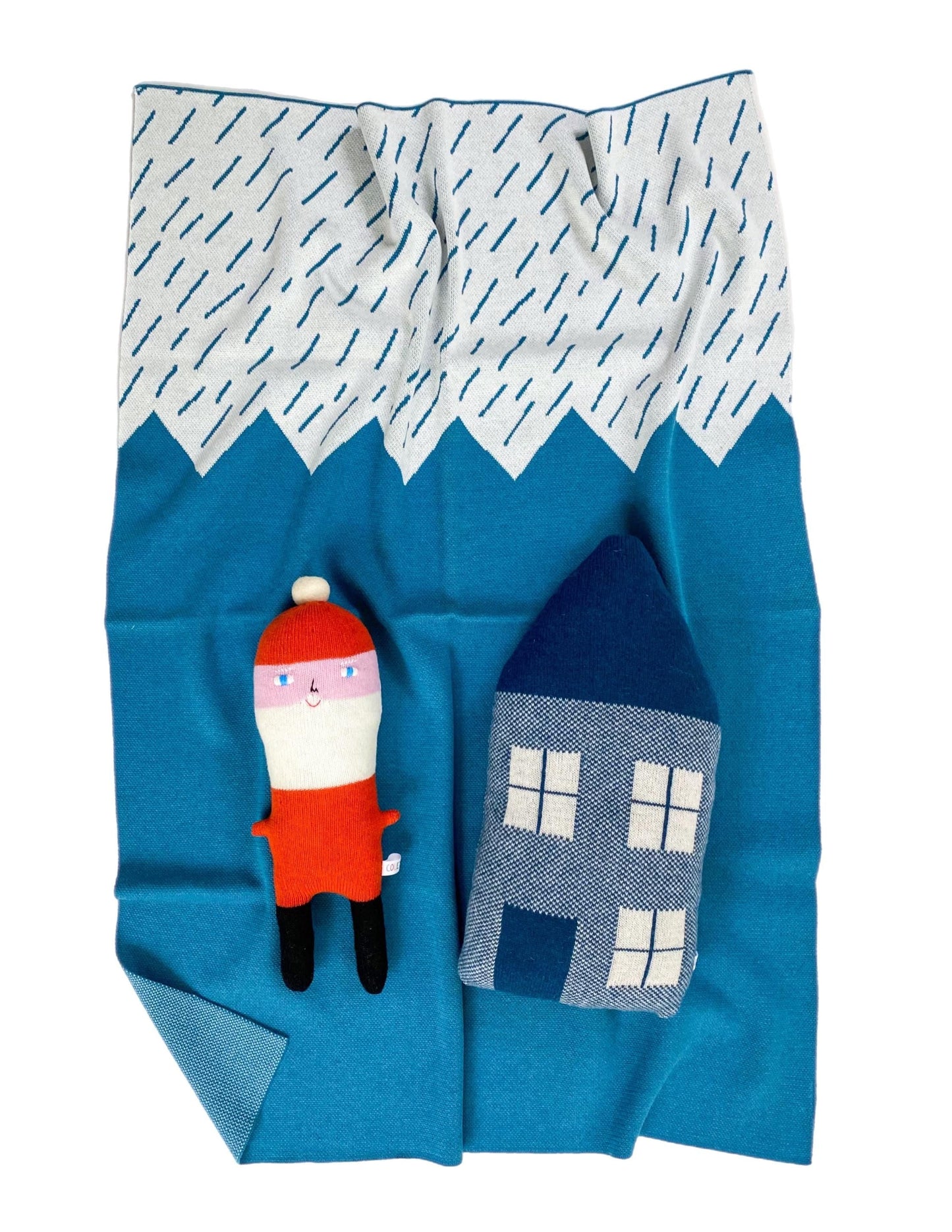 Blue mountain blanket with a Santa Claus toy and a small house shaped pillow cushion on a white background