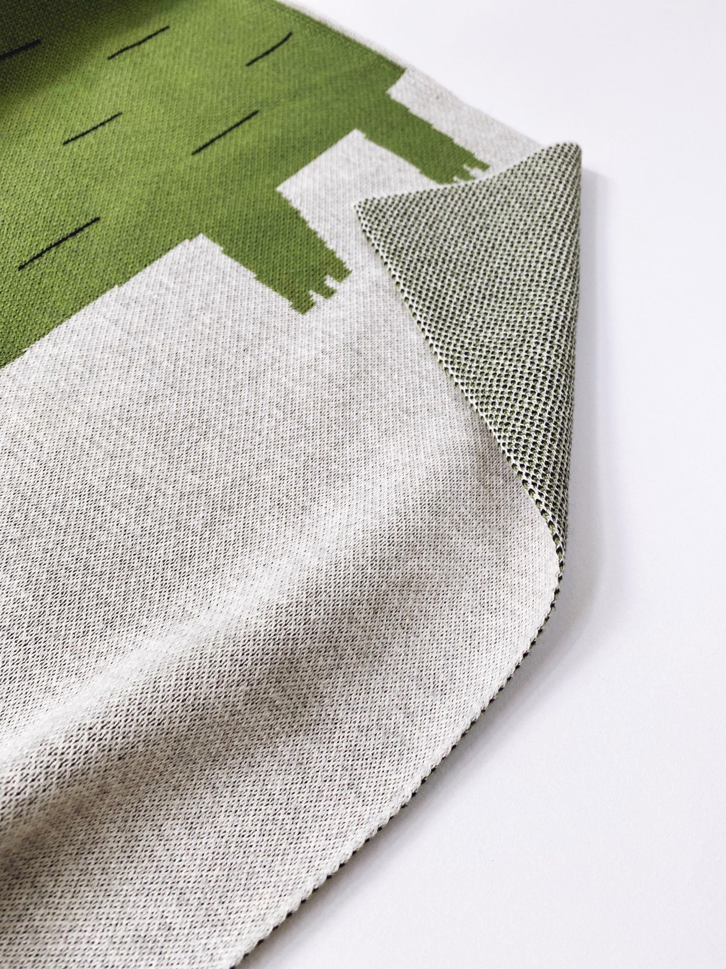 Close-up of a knit fabric with green, white, and gray patterns on a white background