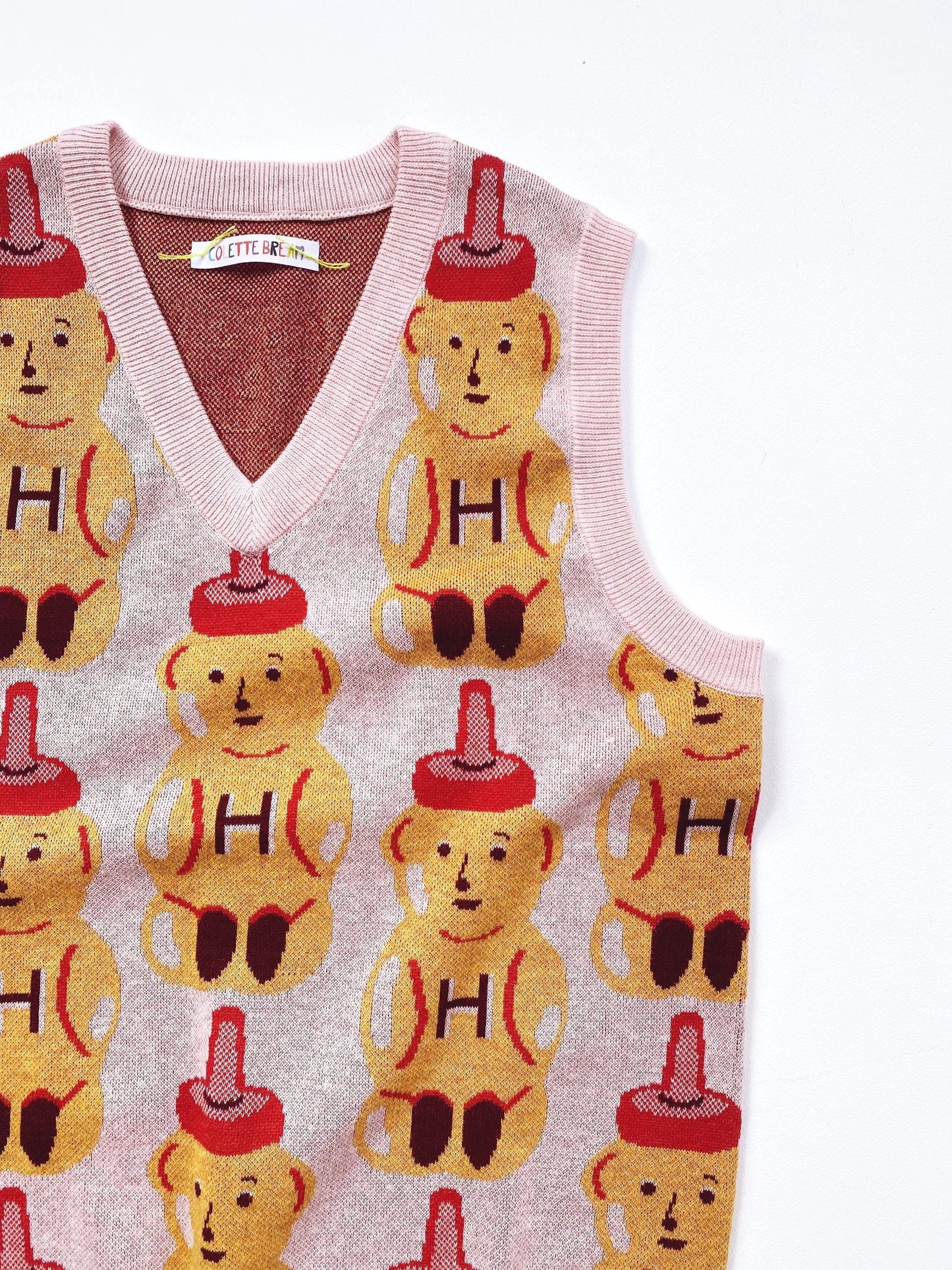 Sweater vest with honey bear pattern and letter 'H' on a white background