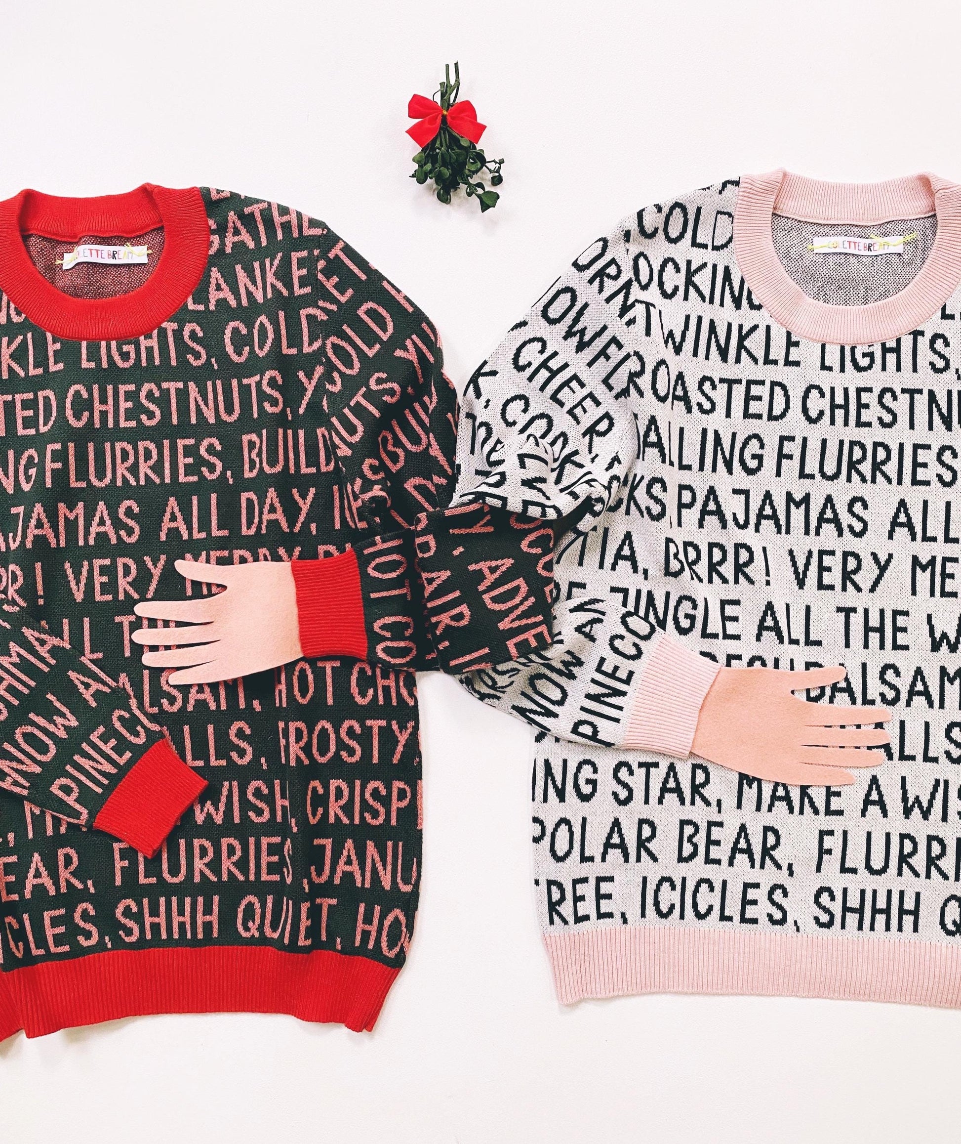 Two sweaters with festive christmas text patterns on a white background