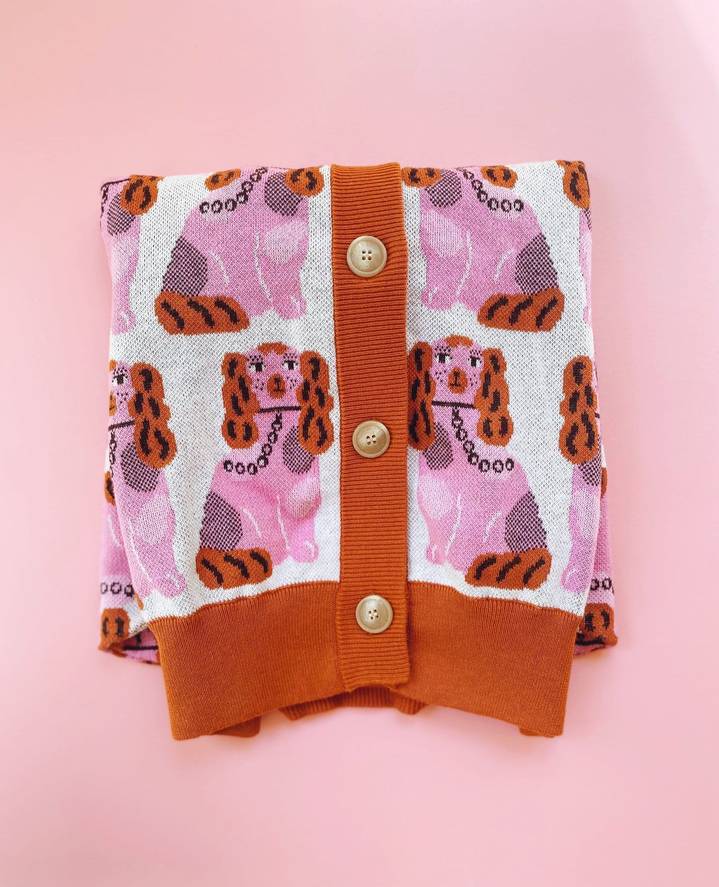 Colorful knitted cardigan sweater with staffordshire dog pattern on a pink background