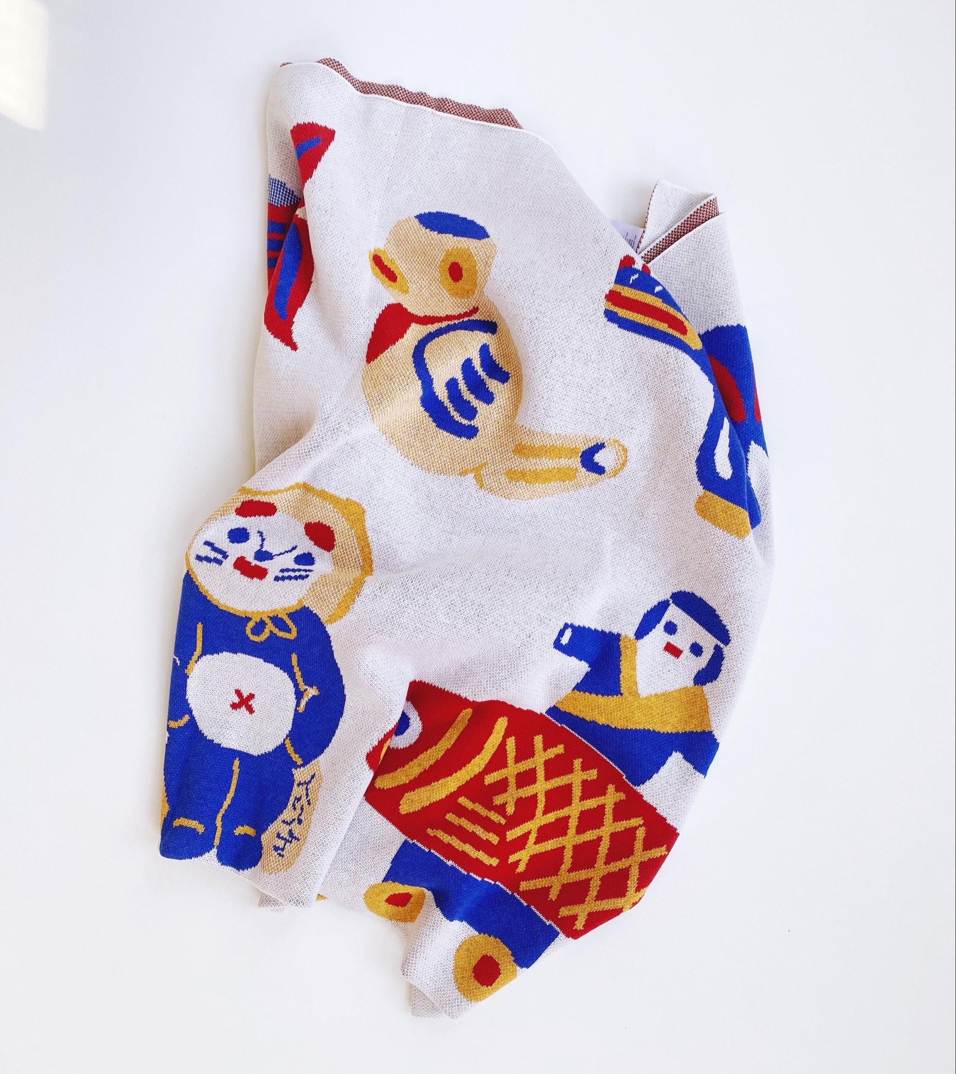 Knitted blanket with colorful cartoon designs and other japanese characters on a white background