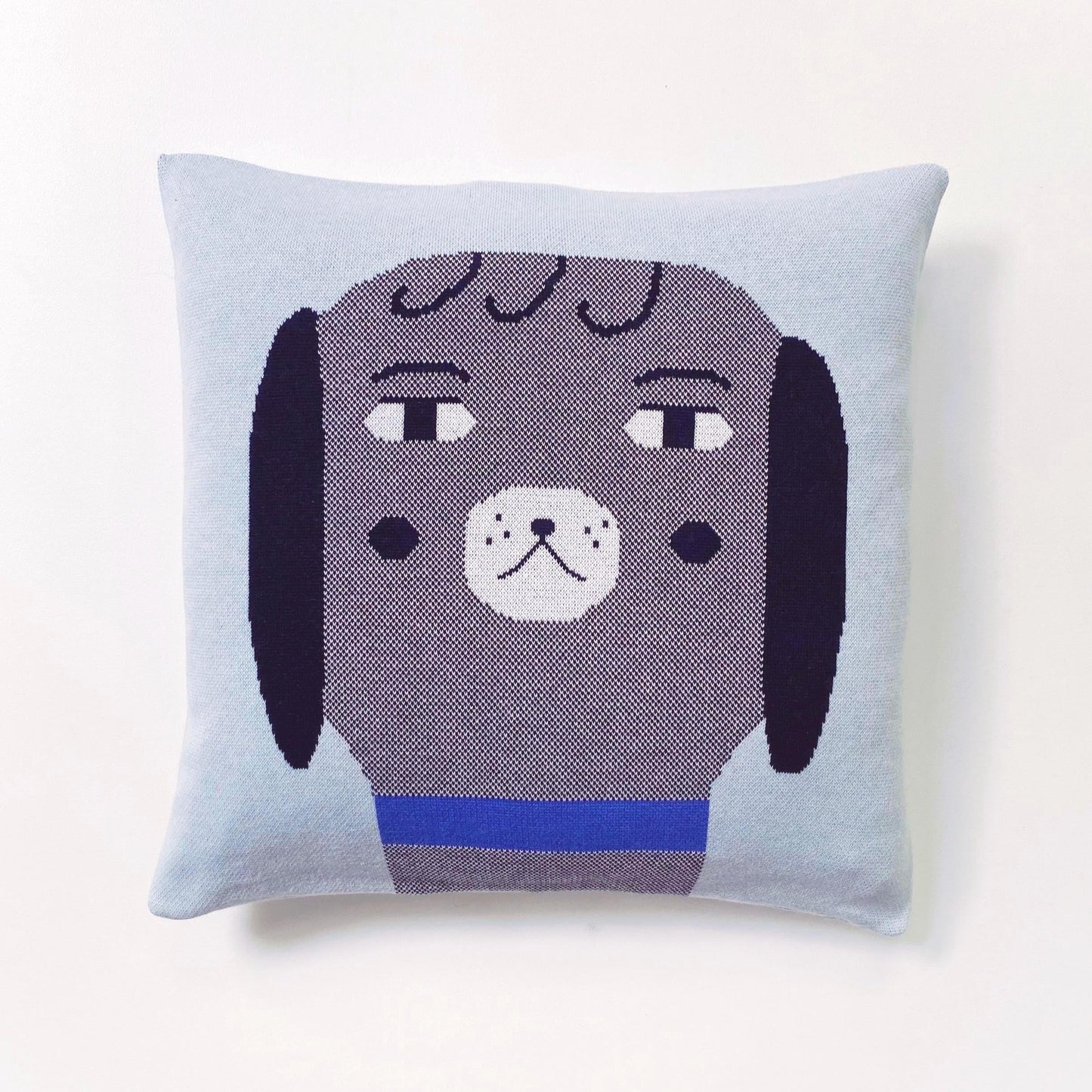 Decorative pillow with a dog face design on a light blue background