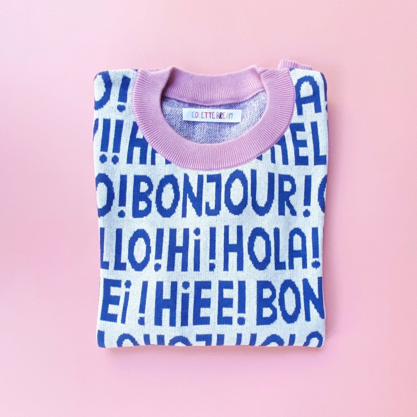 Folded sweater with blue text on a pink background