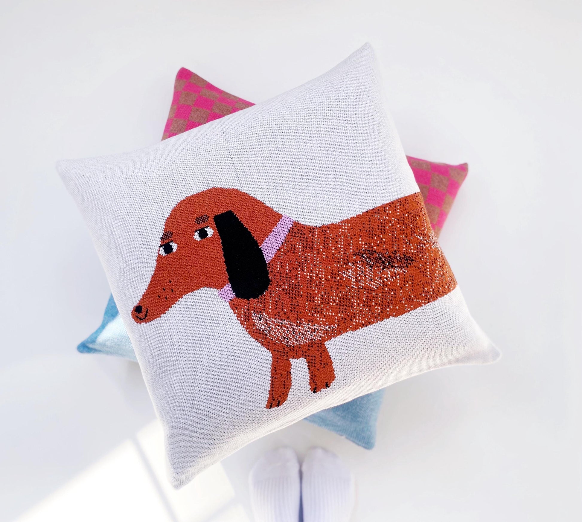 Knitted pillow with a dachshund design on a white background