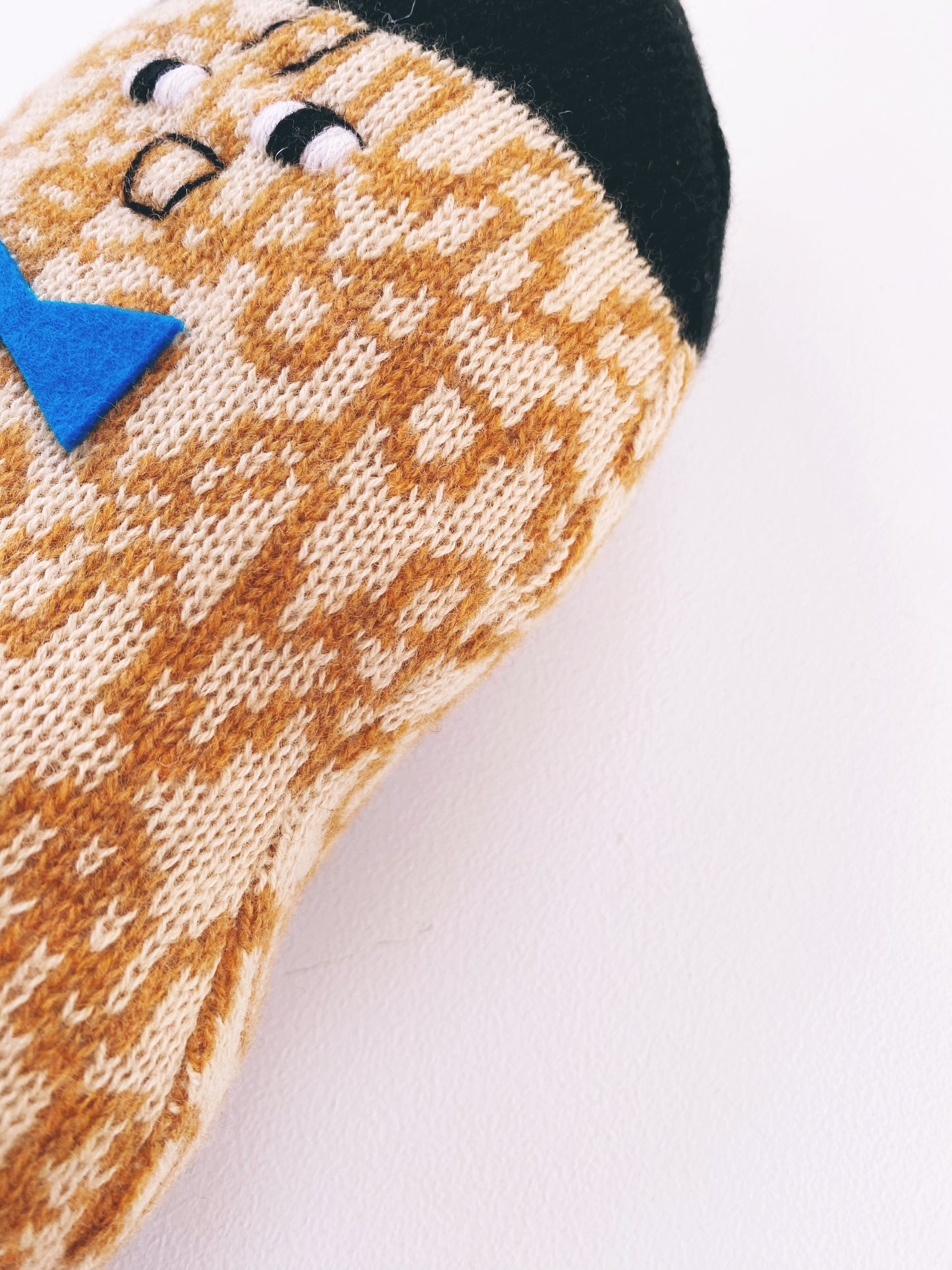 Knitted lambswool peanut toy plush with a face design on a white background