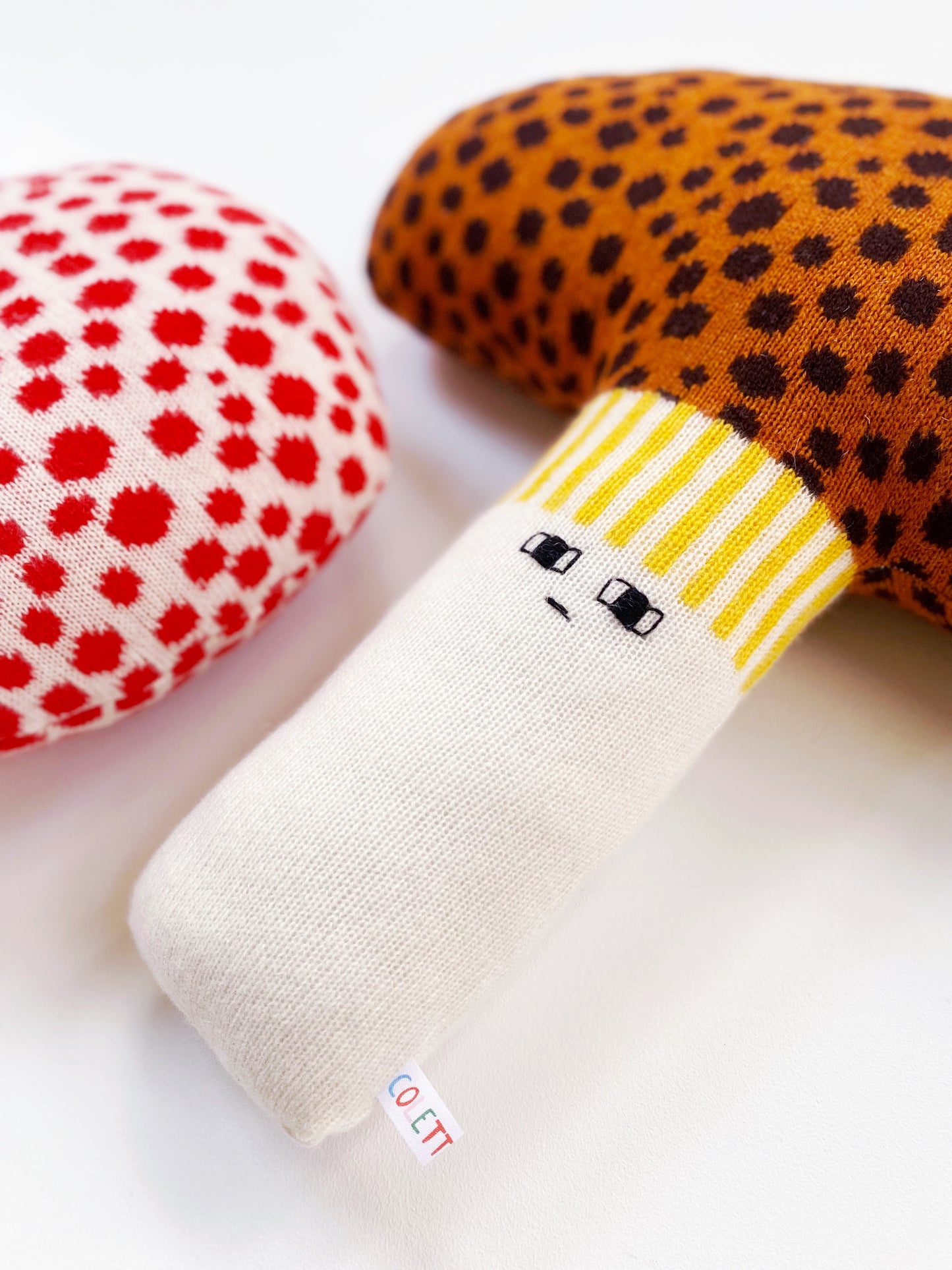 Colorful knitted mushroom pillow cushion character with different patterns on a white background