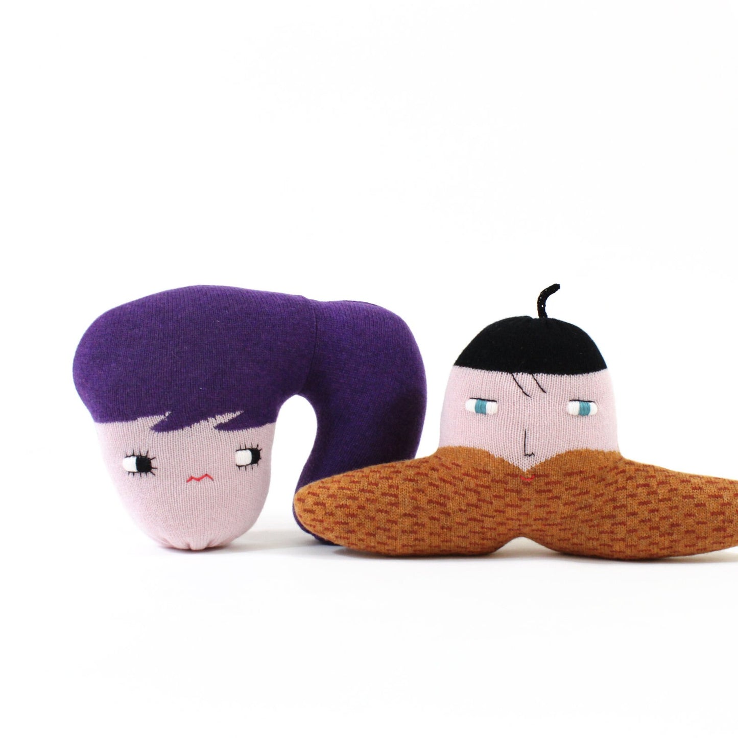 Two plush toys resembling a woman with purple hair and a man with brown hair and a mustache on a white background.