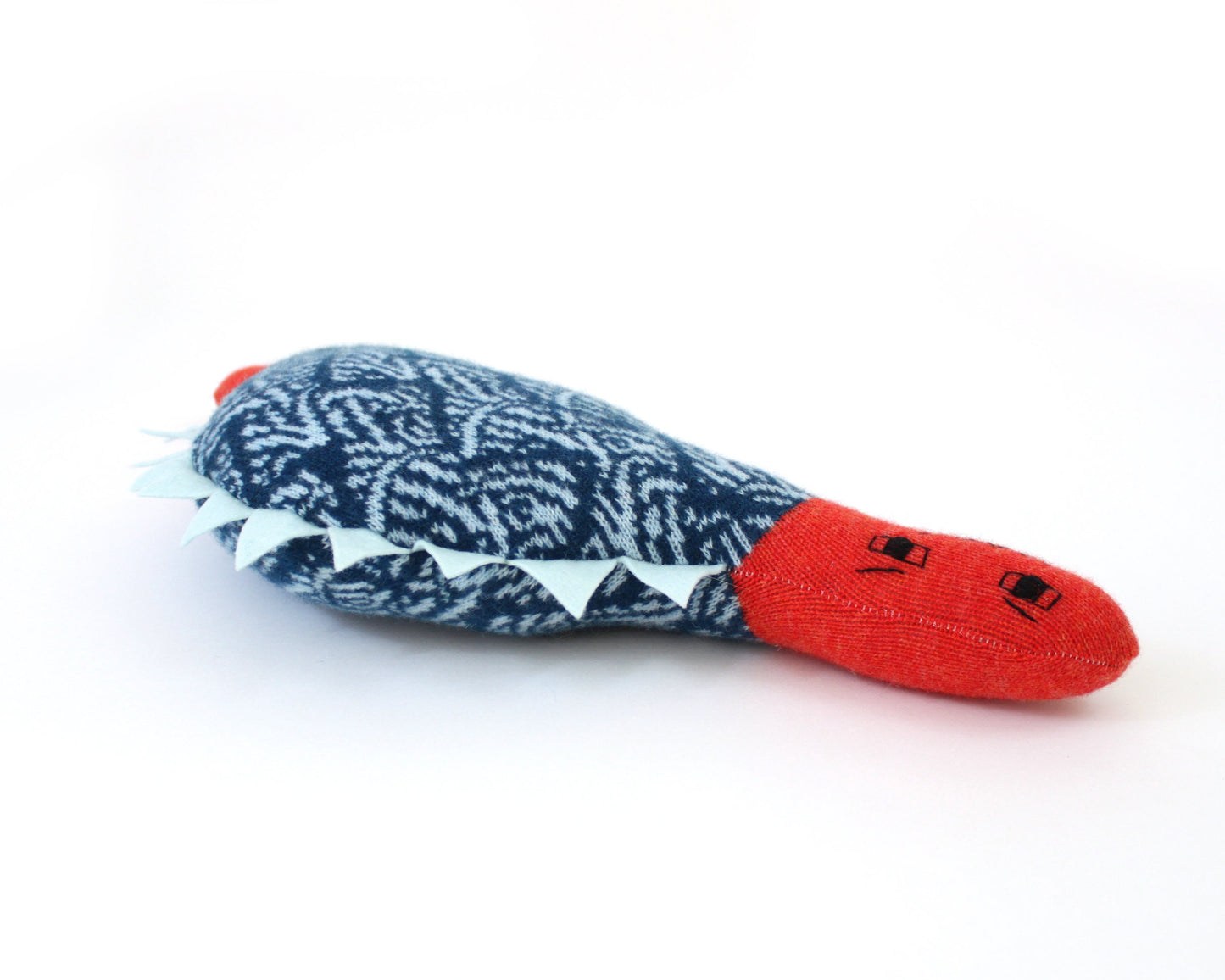 Soft knitted dinosaur plush toy with a red mouth on a white background