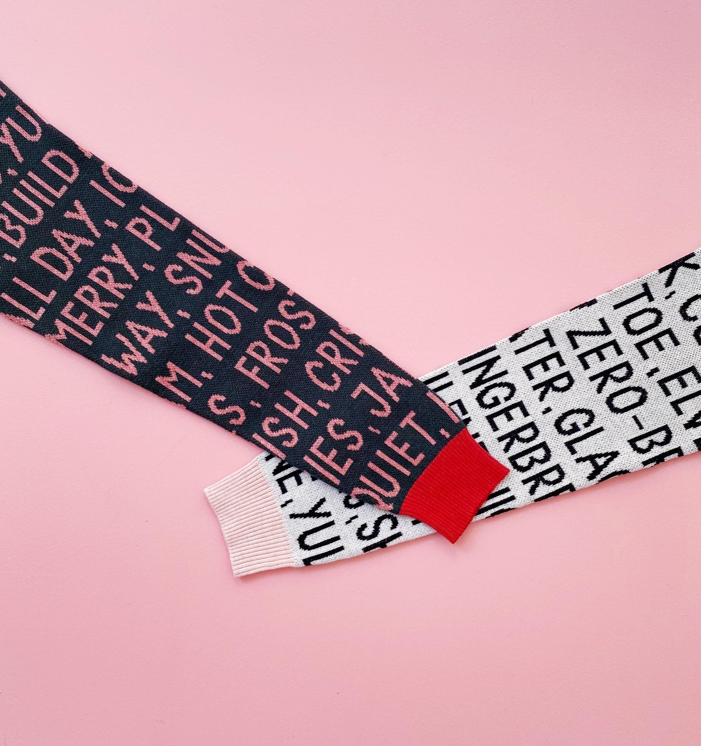 Textured knitted sweater sleeves with black and white festive chrsitmas text pattern on a pink background