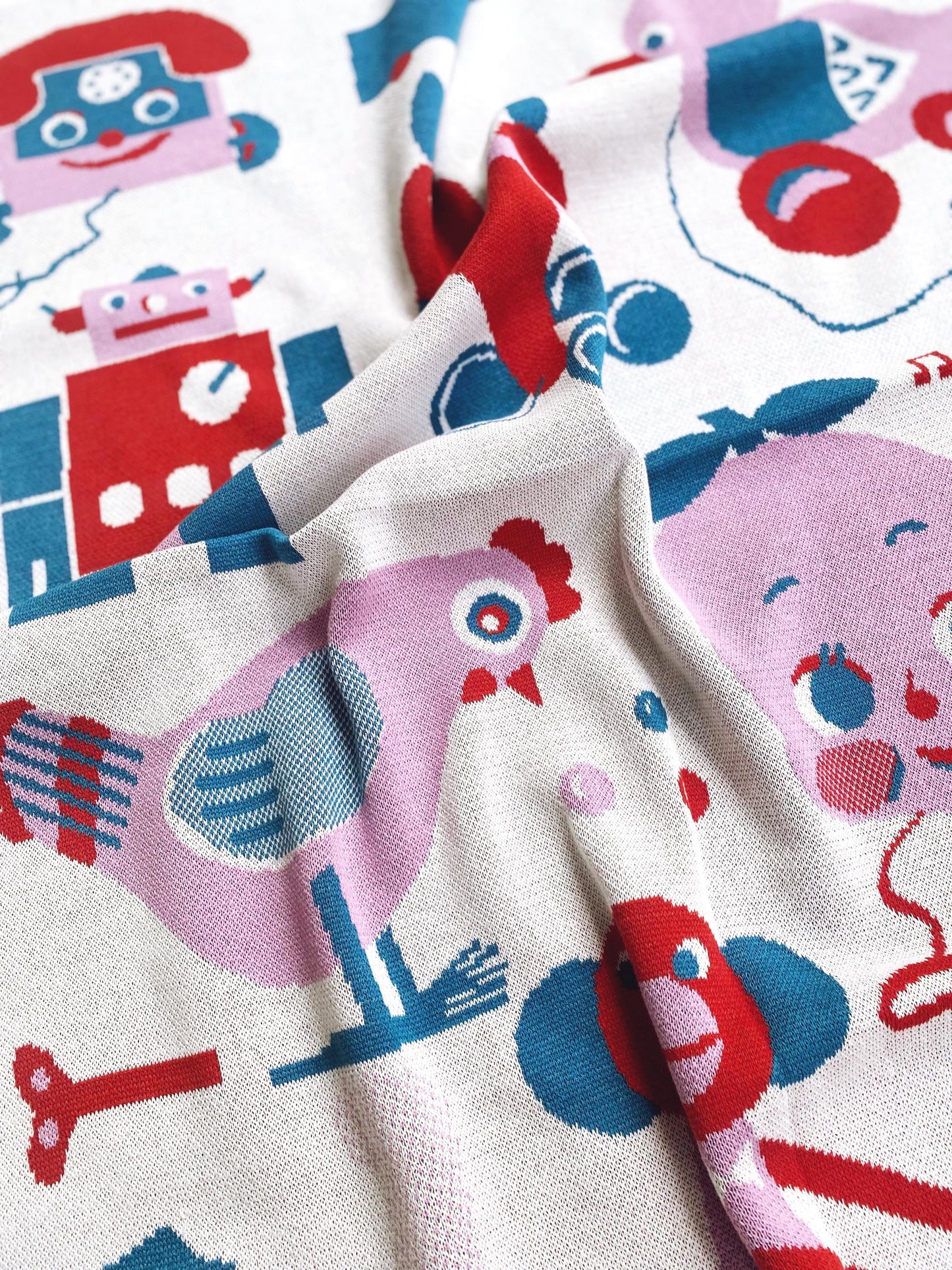 Close-up of a knitted blanket fabric with colorful robot and animal patterns.