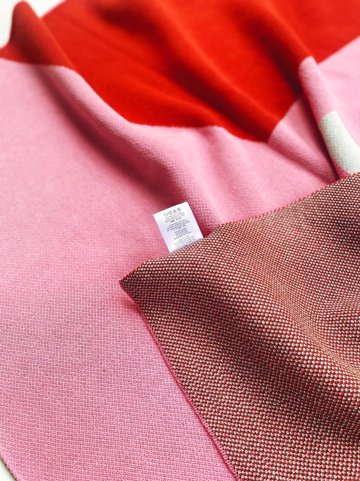 Close-up of knitted fabric with a label on a pink and red background
